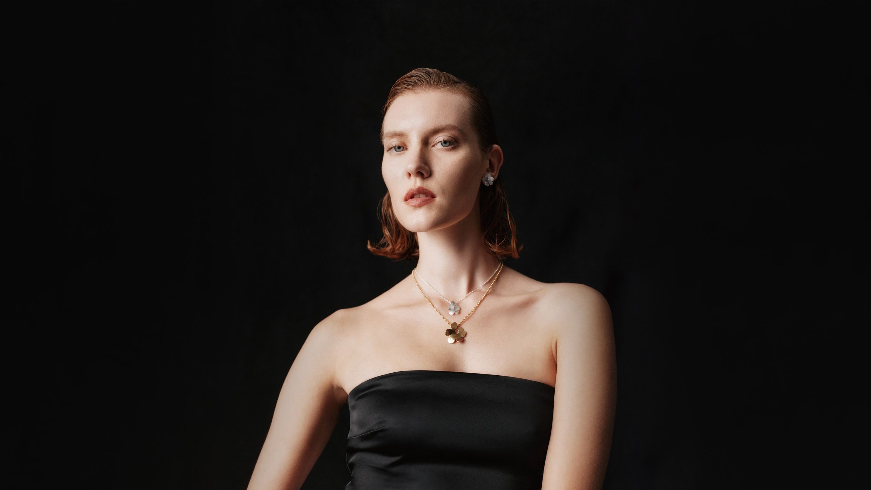 Model wearing Kalevala x Marimekko Unikko necklaces in silver and gold.