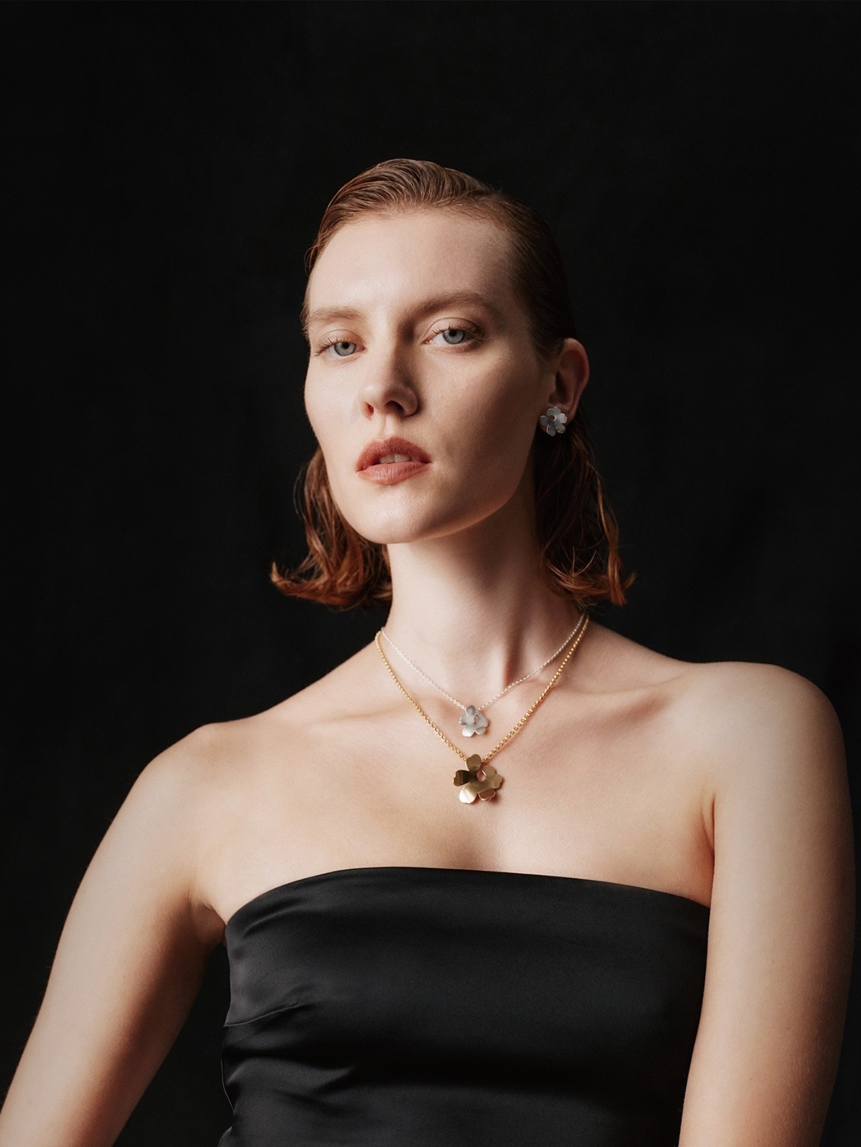 Model wearing Kalevala x Marimekko Unikko necklaces in silver and gold.