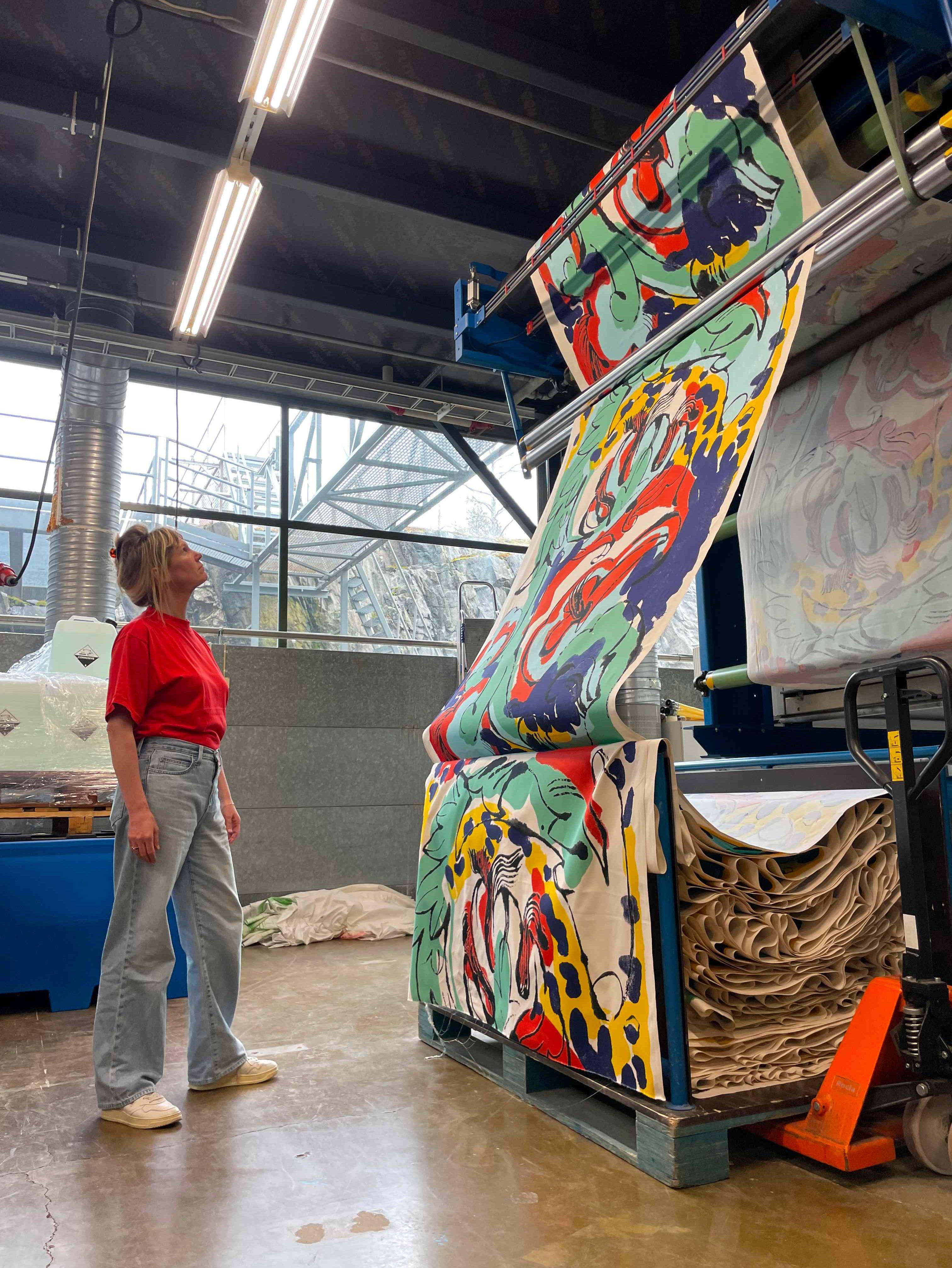 Petra Börner in Marimekko's printing mill watching newly printed fabric in the pattern she has created as part of her collaboration with Marimekko.