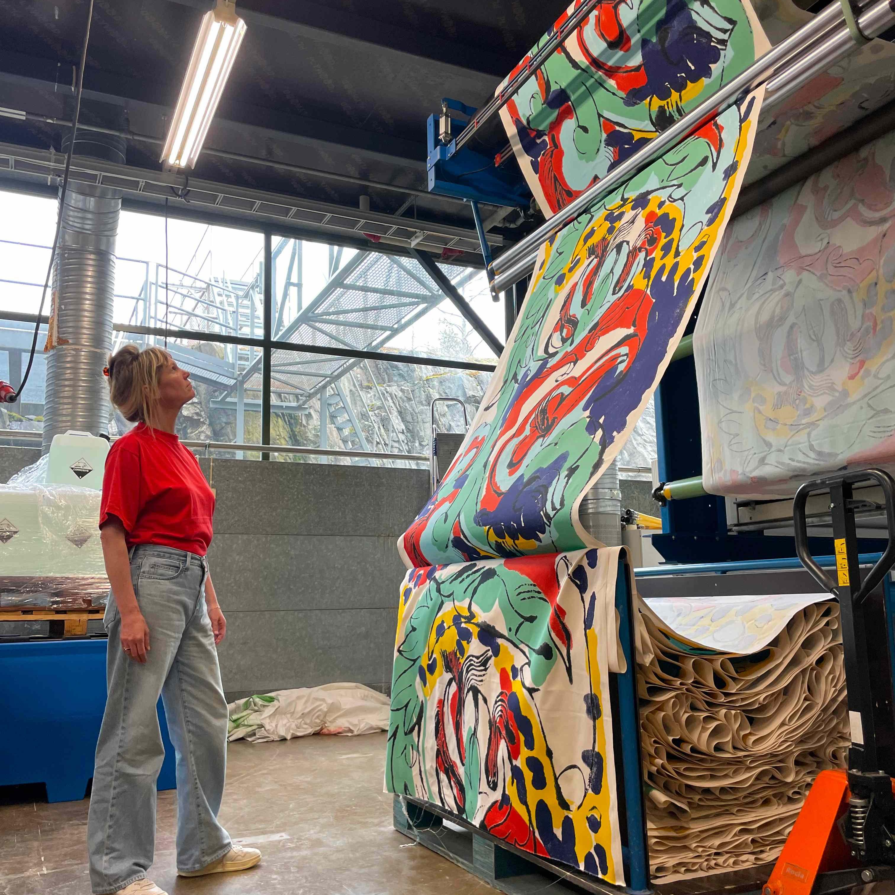 Petra Börner in Marimekko's printing mill watching newly printed fabric in the pattern she has created as part of her collaboration with Marimekko.