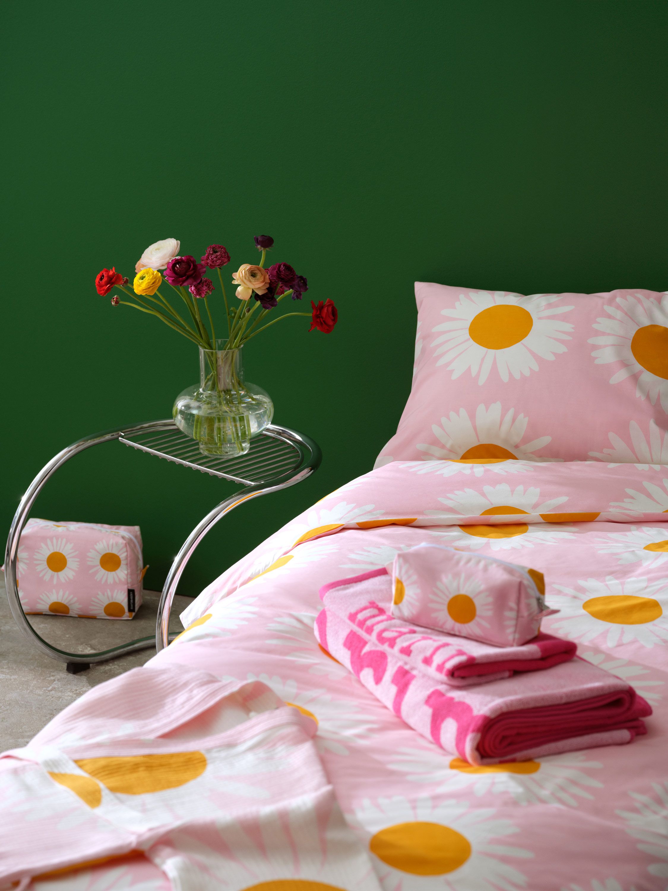 Pedattu sänky, jossa Auringonkukka-lakanat ja Marimerkki-kuosi pyyhkeitä.