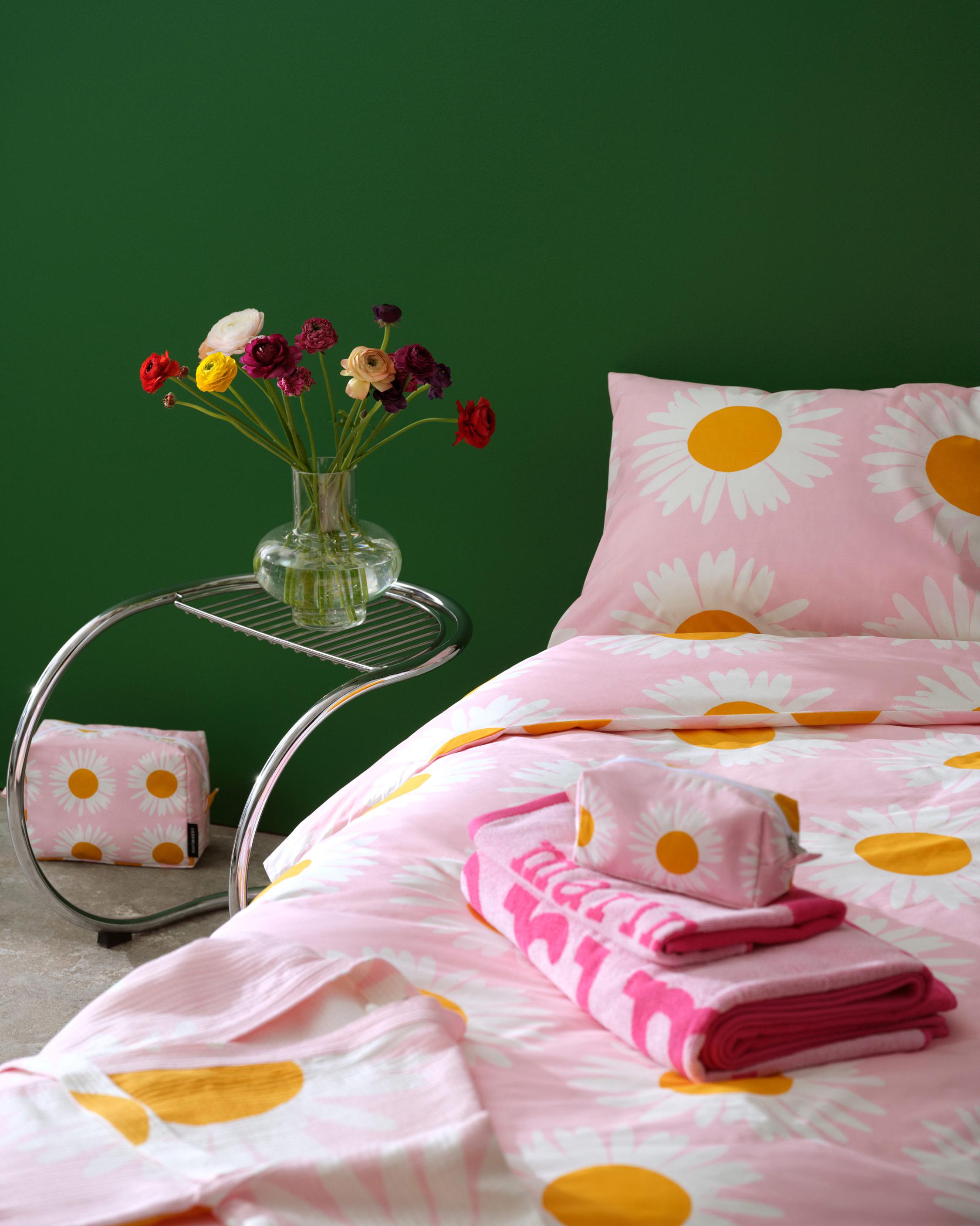Pedattu sänky, jossa Auringonkukka-lakanat ja Marimerkki-kuosi pyyhkeitä.