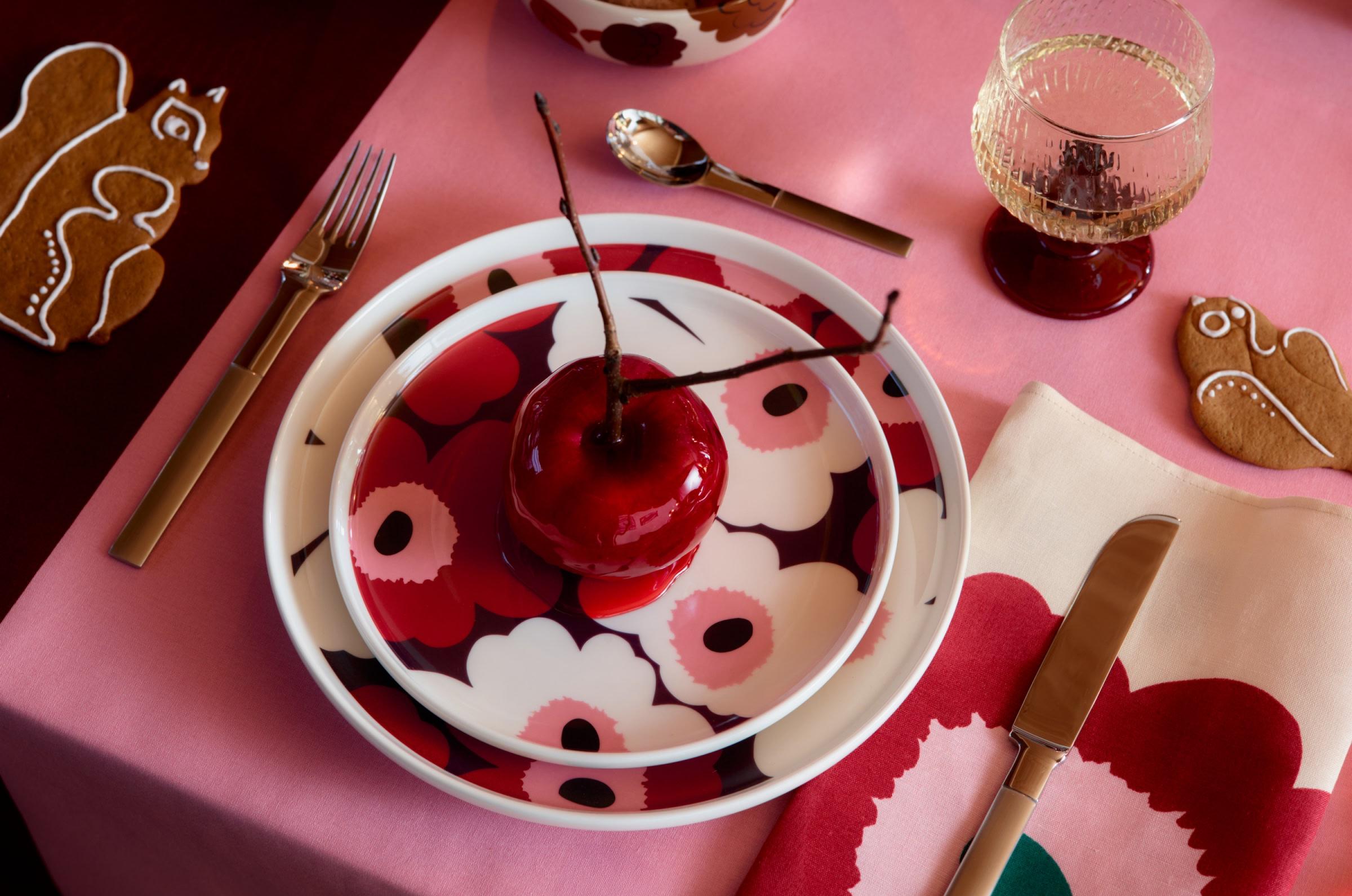 Red, pink, and white Unikko-print tableware arranged on a table with Syksy glassware and Kurre-shaped cookies.