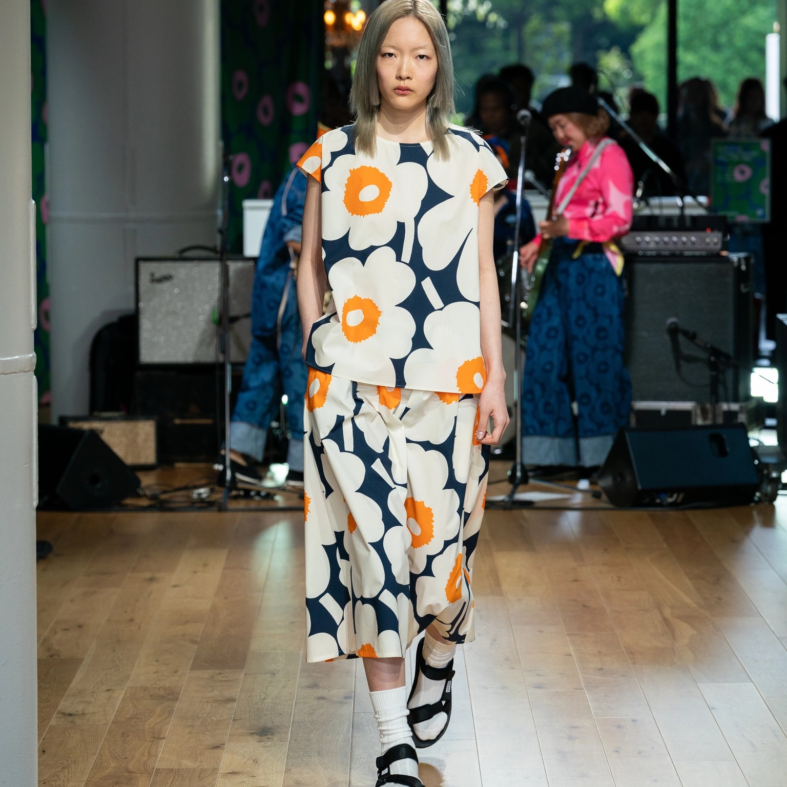 Model wearing blue-white-orange t-shirt and skirt in Unikko pattern.