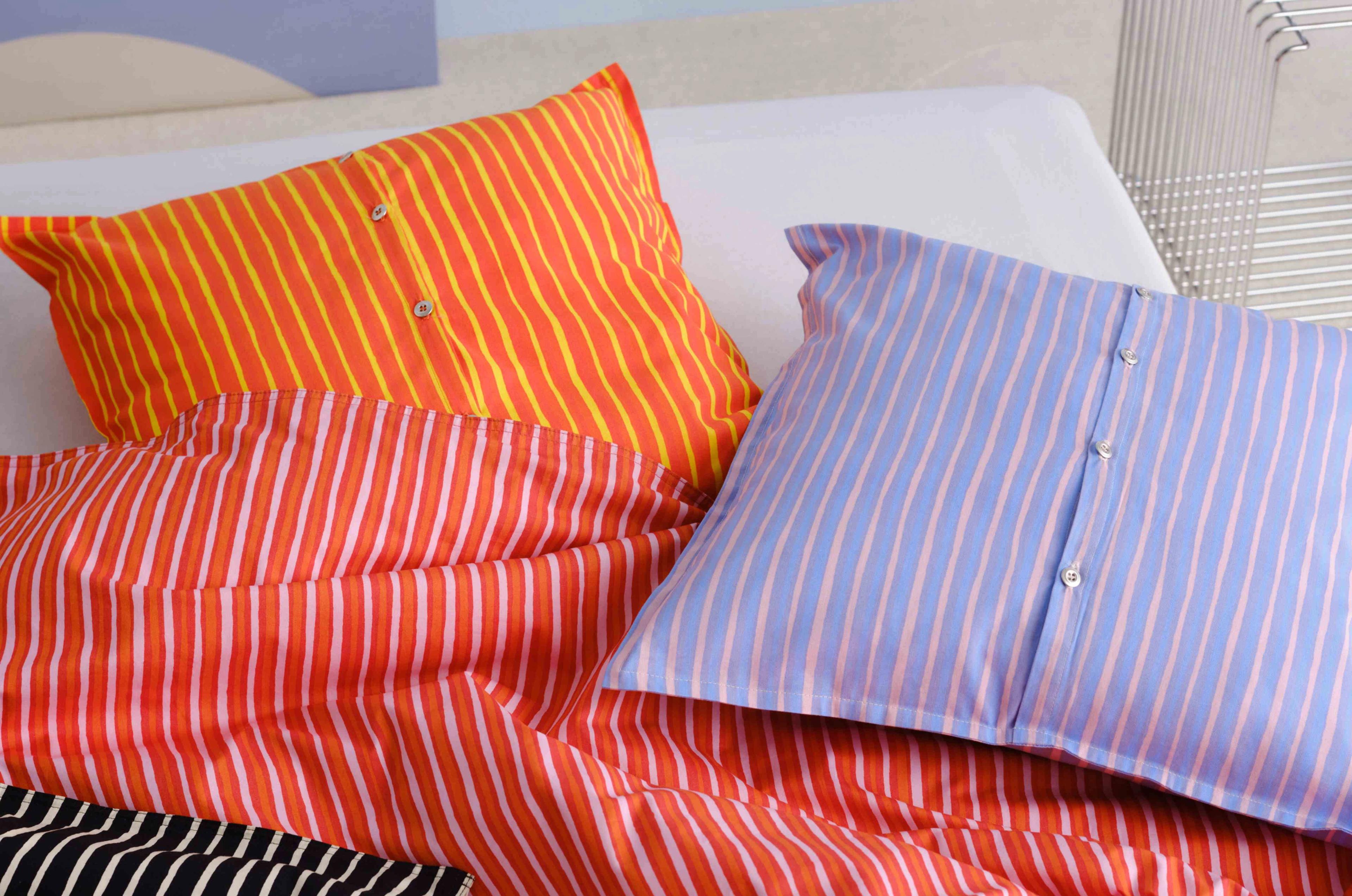 Bed covered with red, orange, and lilac Piccolo print duvet and cushion covers