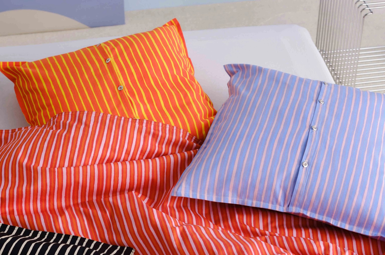 Bed covered with red, orange, and lilac Piccolo print duvet and cushion covers