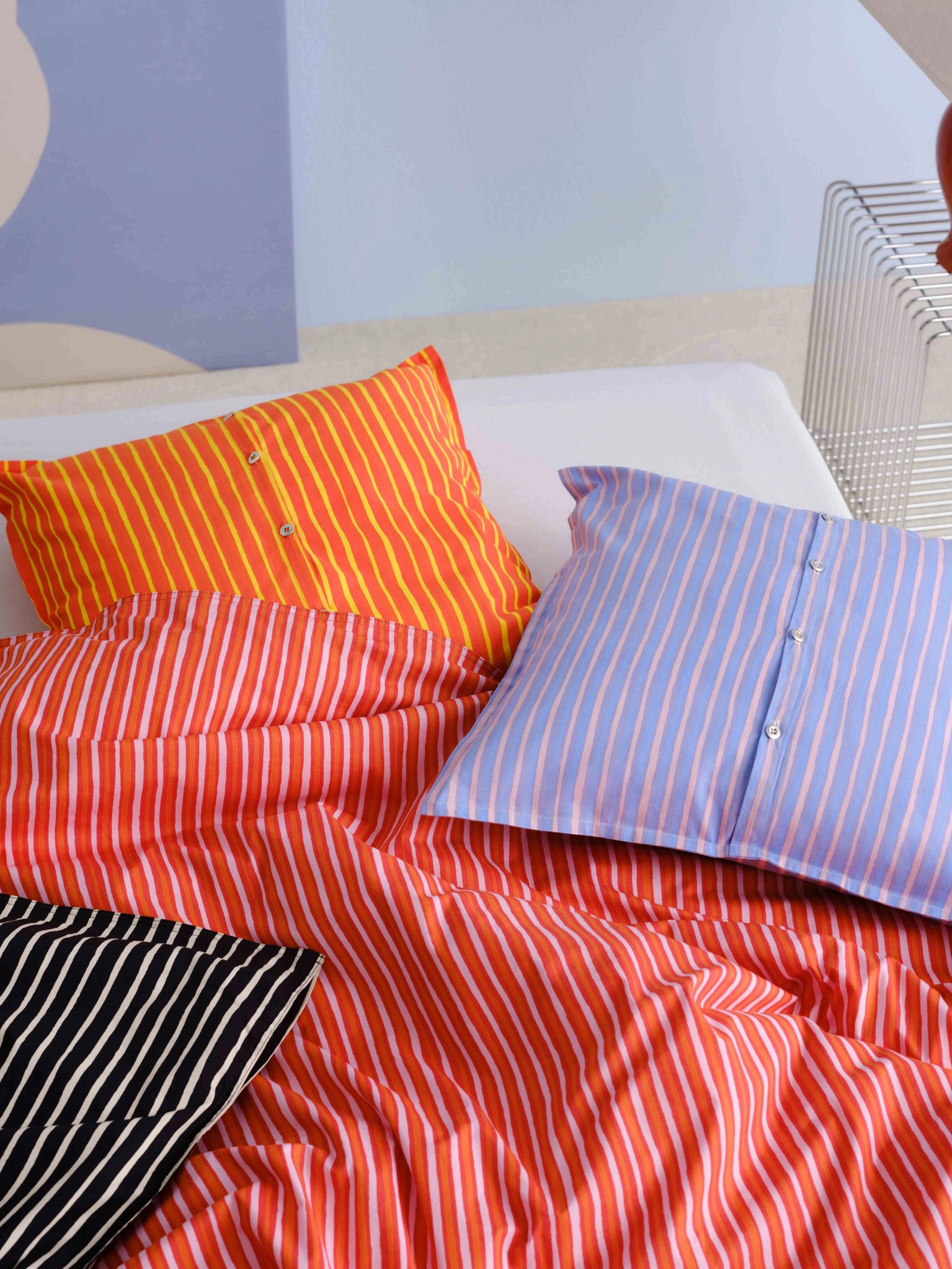 Bed covered with red, orange, and lilac Piccolo print duvet and cushion covers