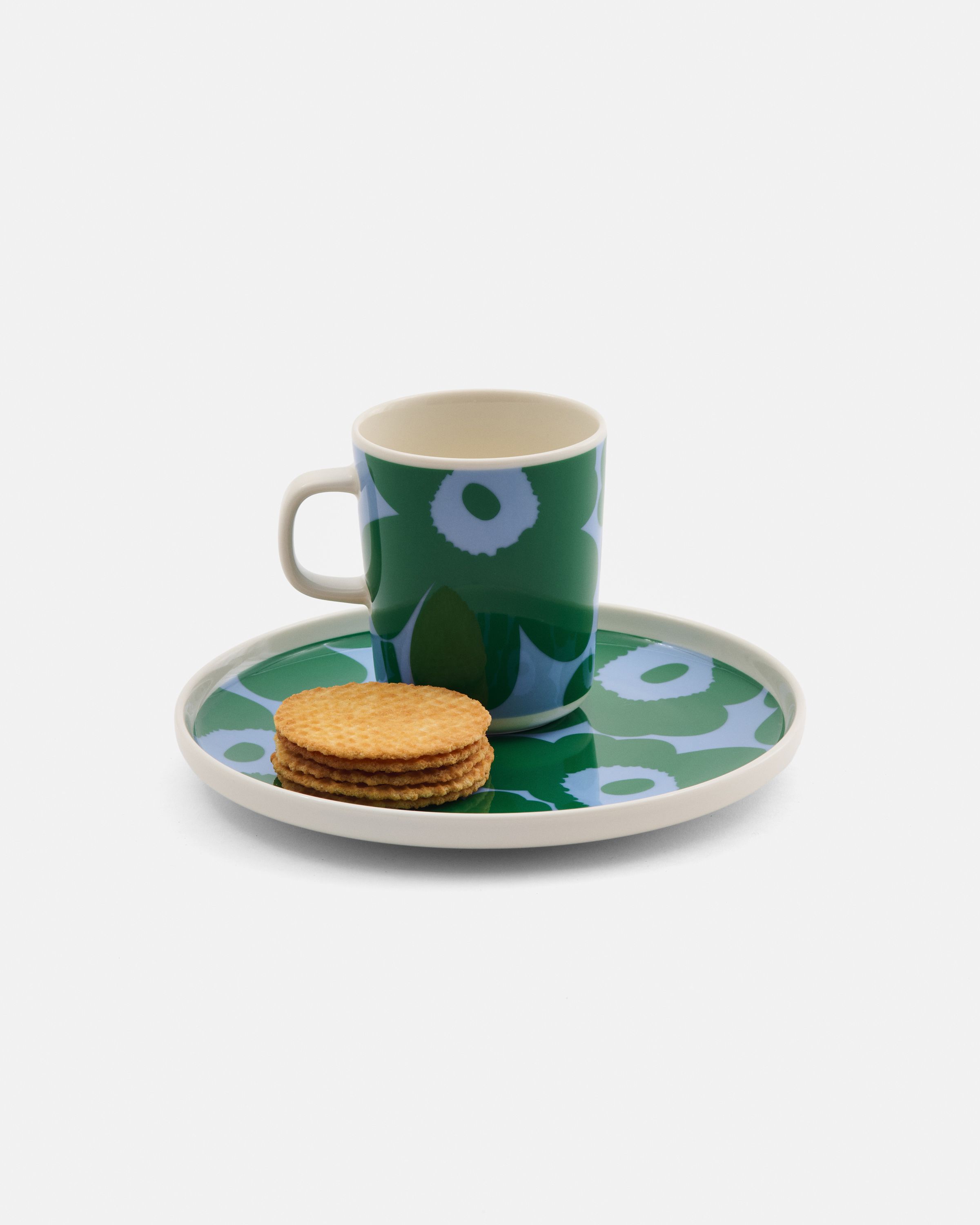 Mug and plate in green and blue Unikko pattern and cookies on the plate.
