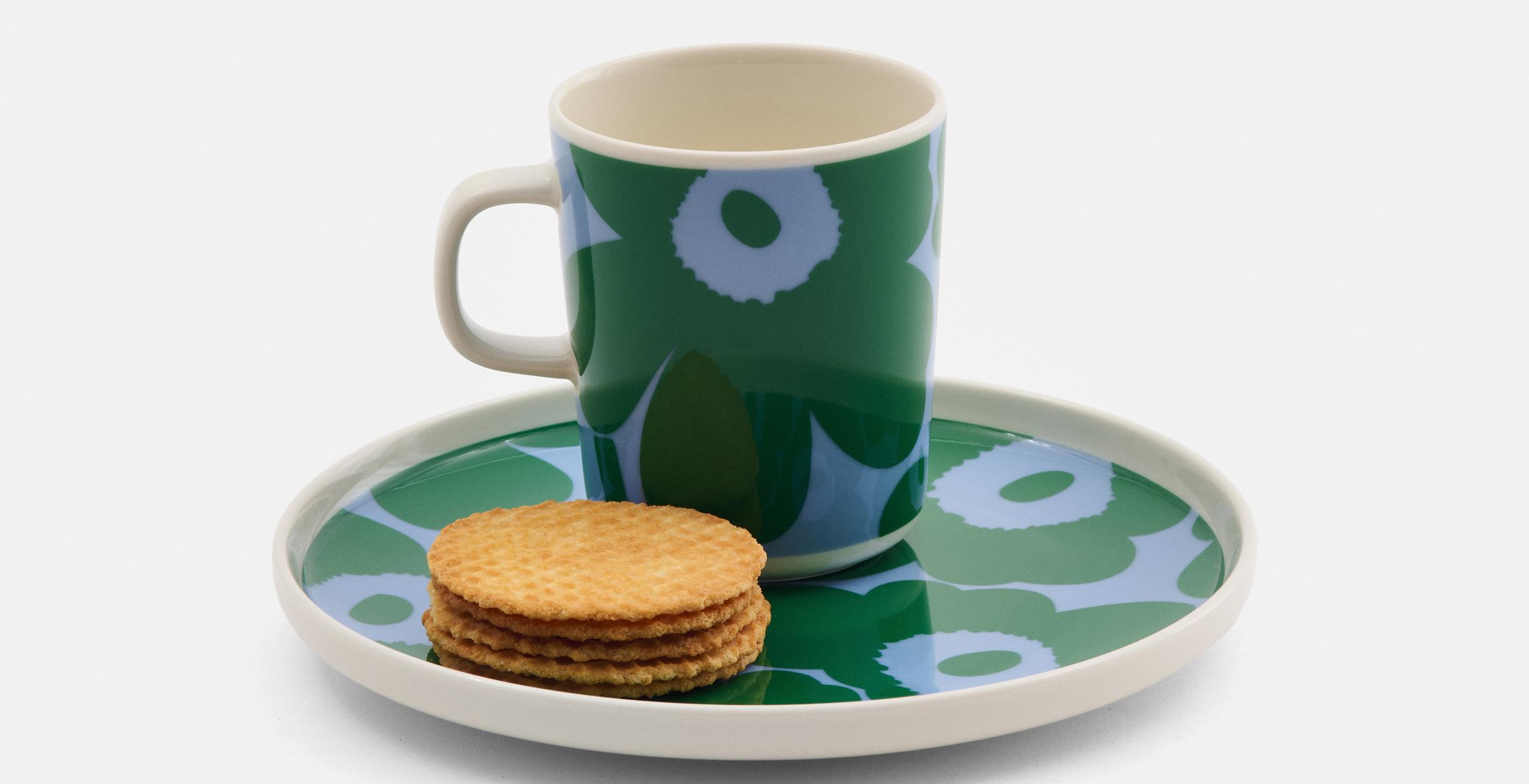 Mug and plate in green and blue Unikko pattern and cookies on the plate.