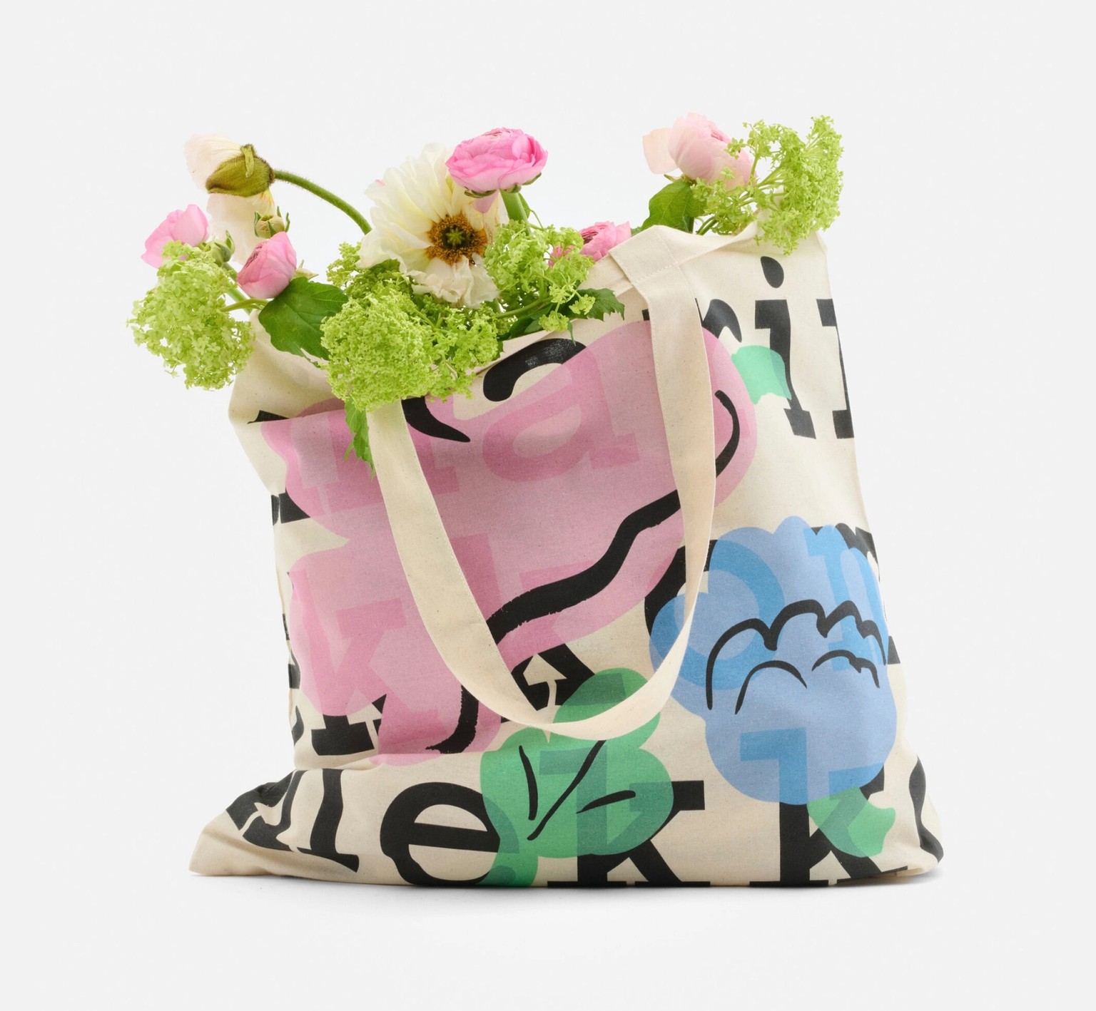 Logo tote, with a logo text and Kukasta kukkaan print, filled with flowers.