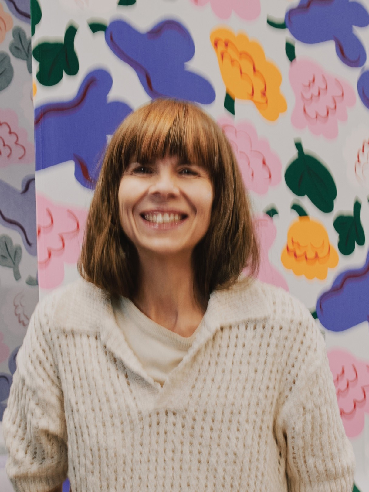 Portrait of Erja Hirvi infront of Kukasta kukkaan print.