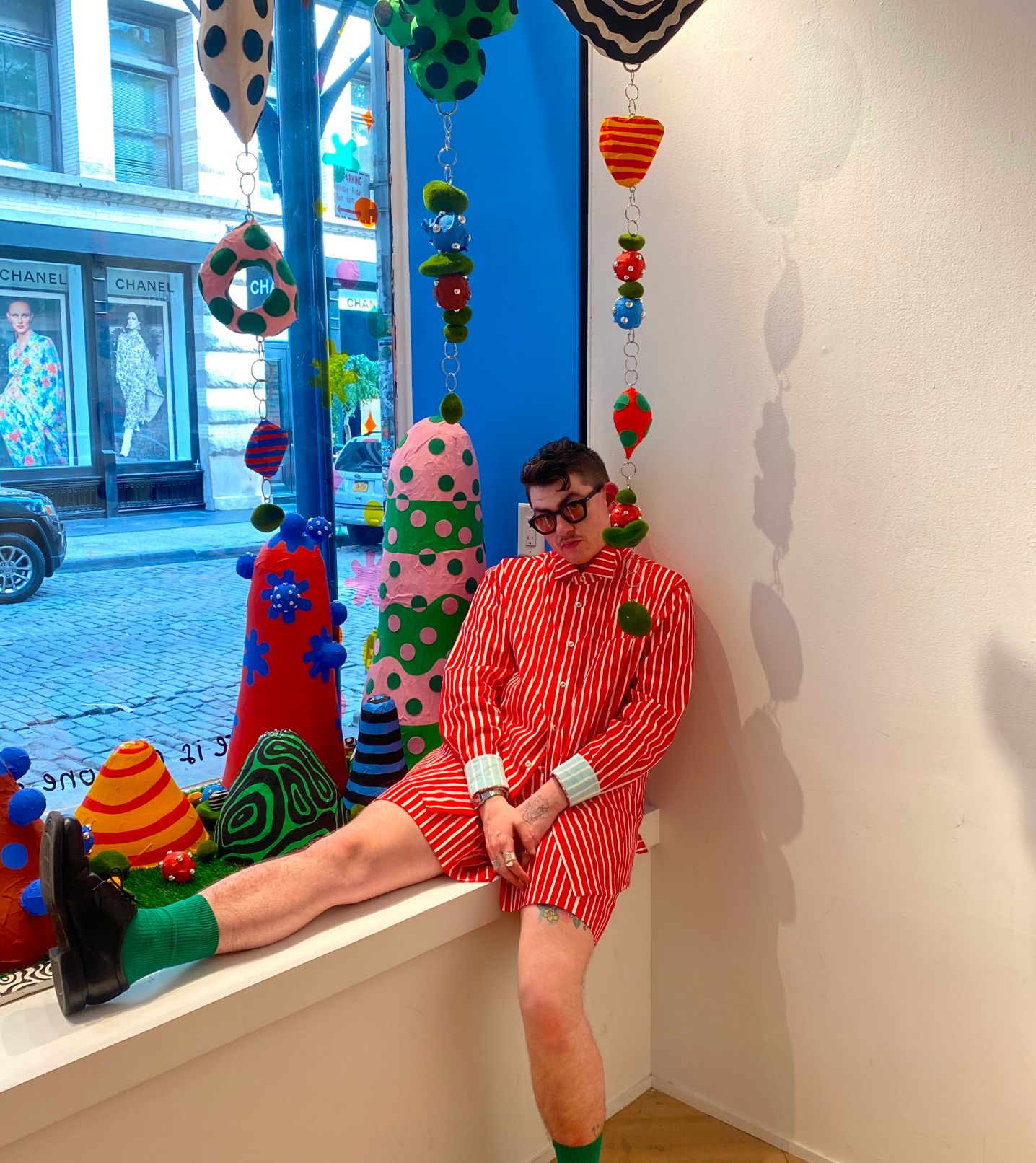 Zander Schlacter posing in front of a window he designed in a New York store.