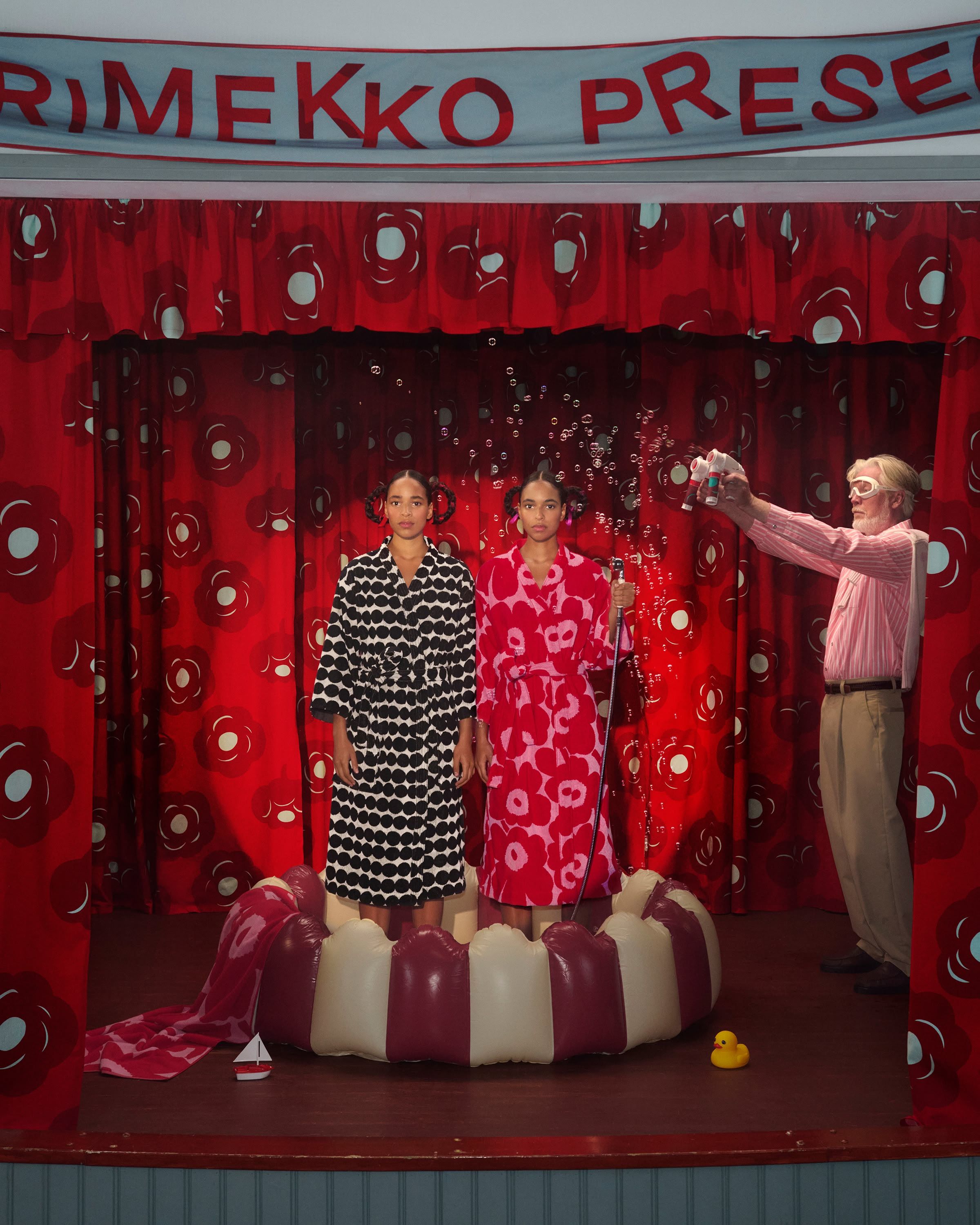 Two models in bathrobes standing on a stage.