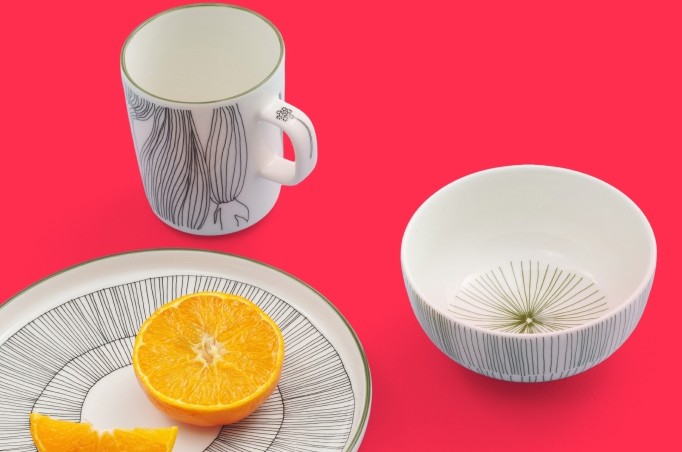 Kukat Puhkeavat muki, lautanen ja kulho punaisella alustalla.