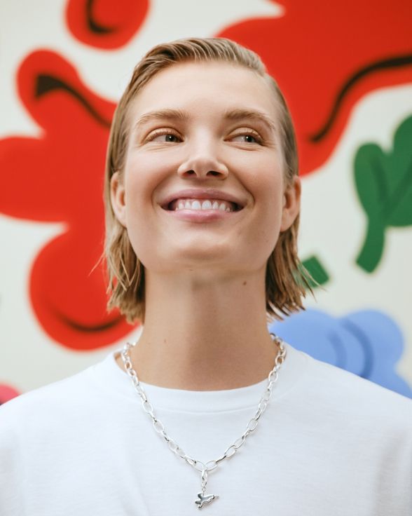 Model posing infront of Kukasta kukkaan print with a Kalevala x Marimekko Garden necklace.