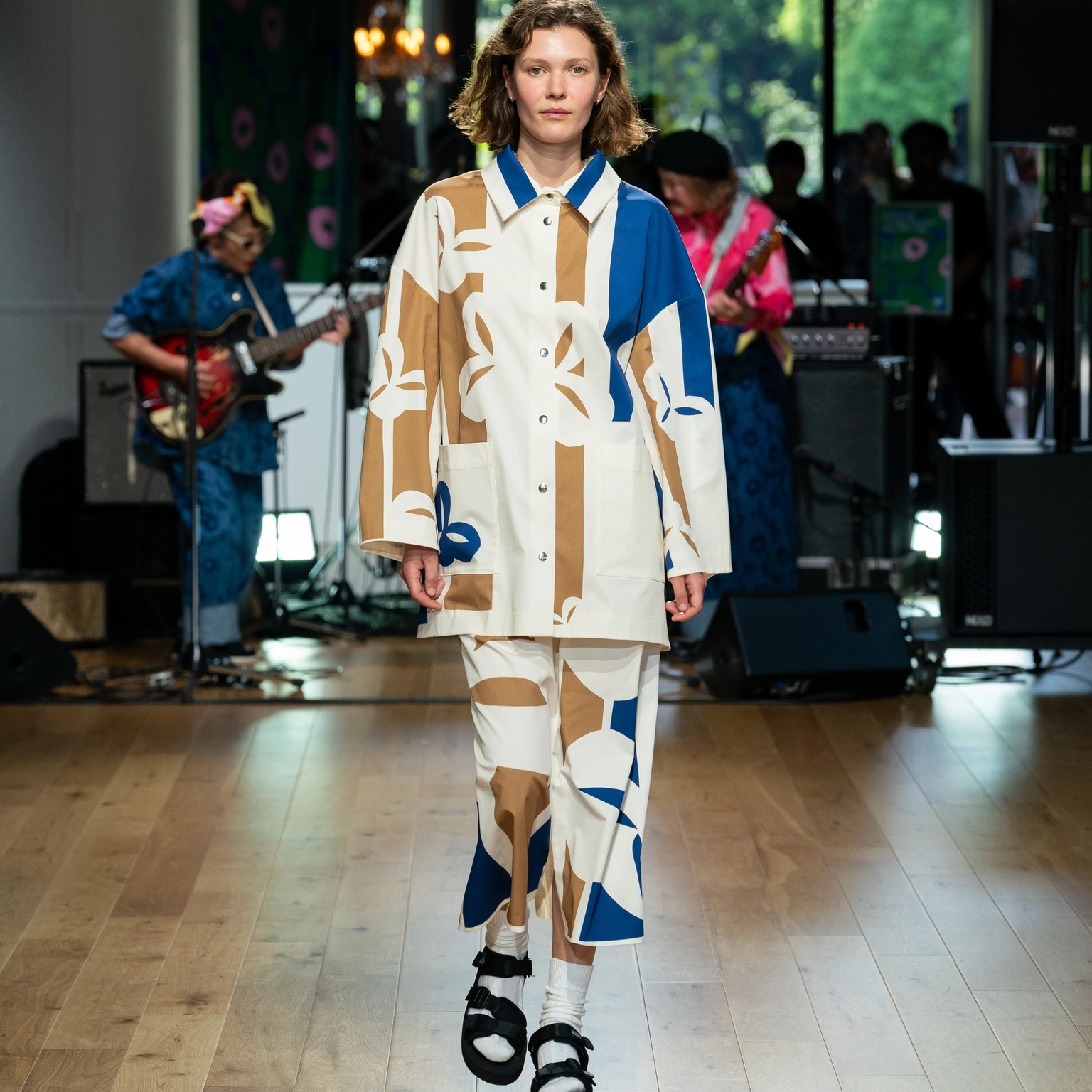 Model wearing white-beige-blue jacket and skirt.