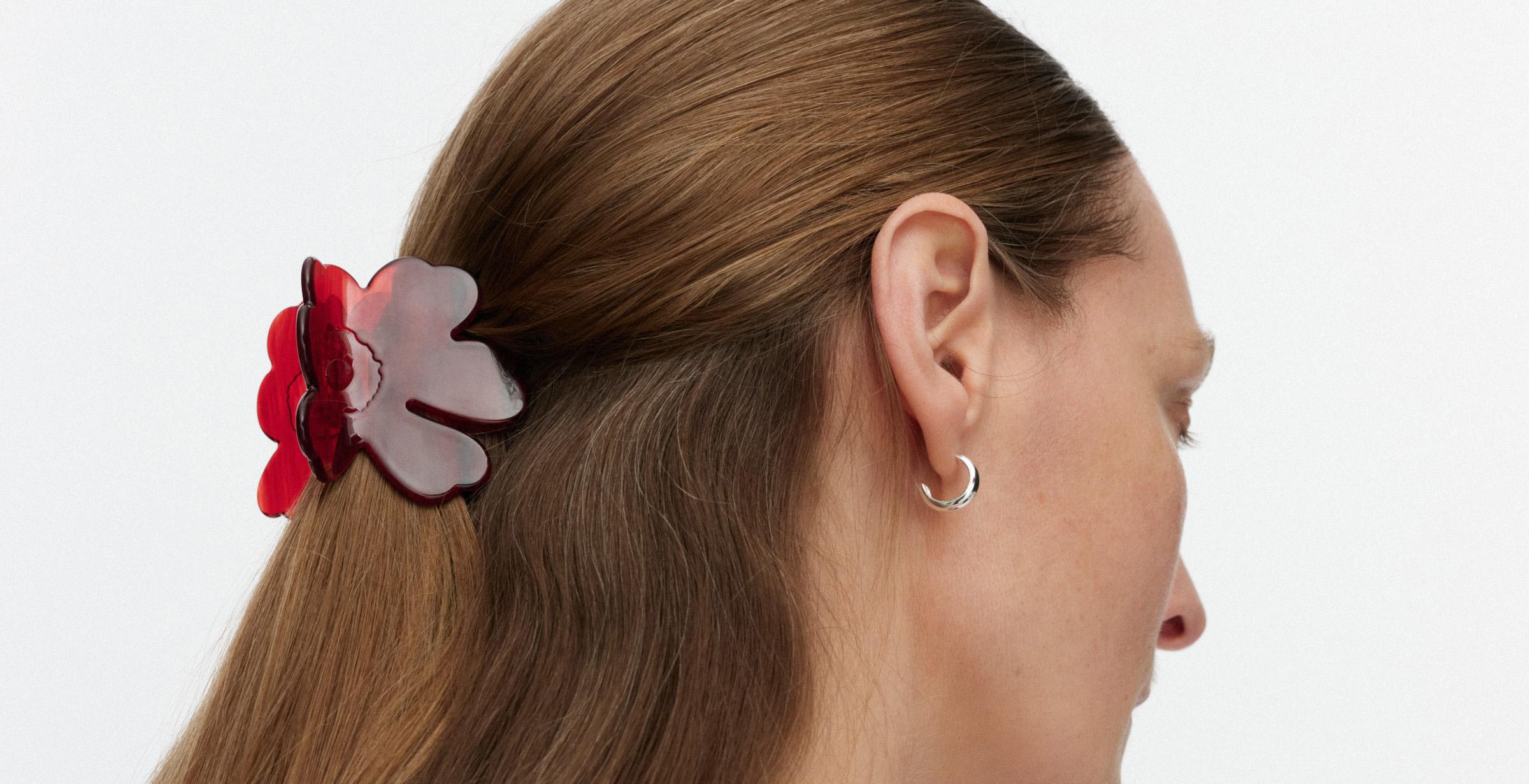 Model wearing a small red Unikko-shaped hair clip.