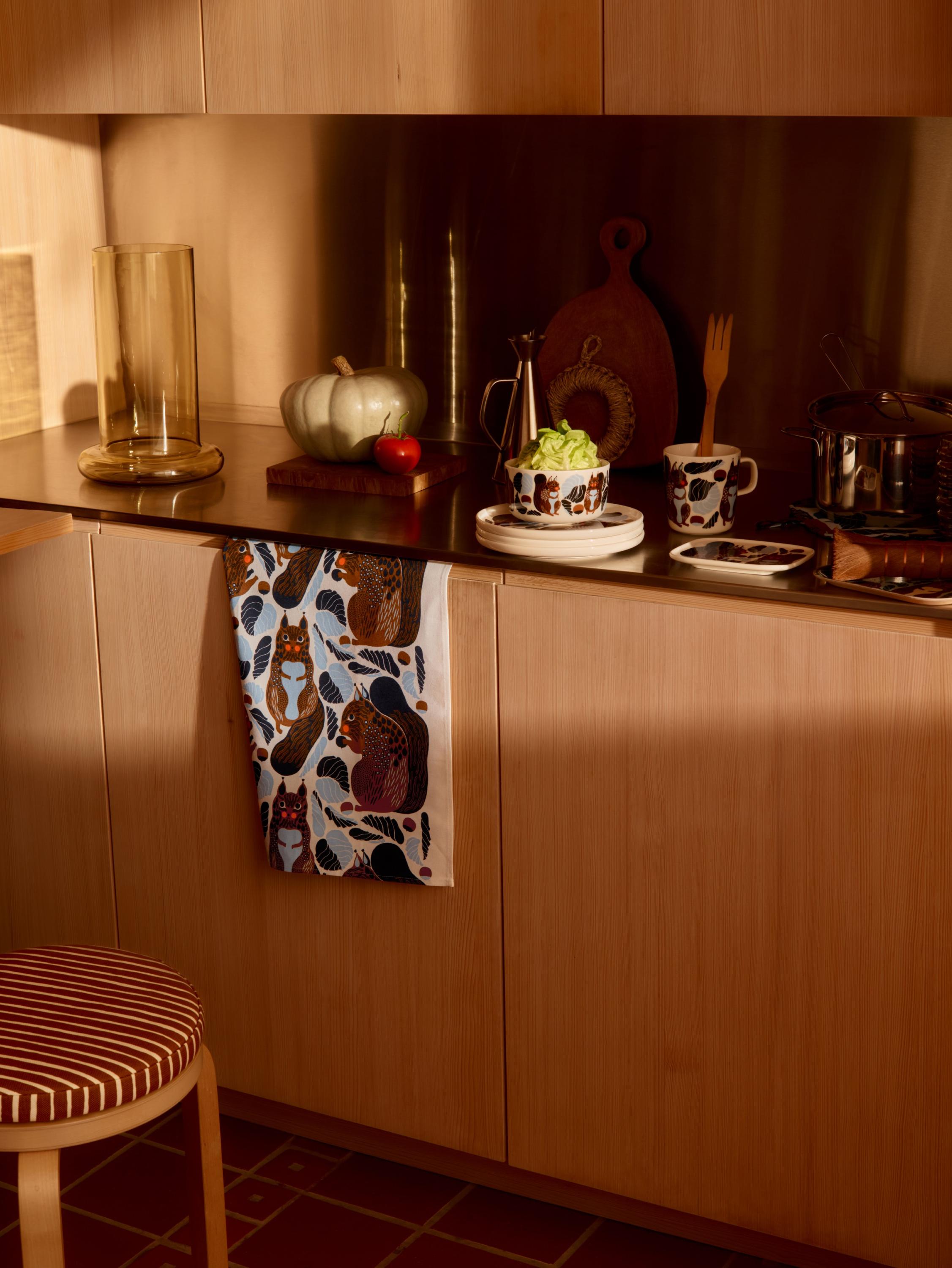 Marimekko ceramic tableware and a matching Kurre-print kitchen towel on a kitchen counter.