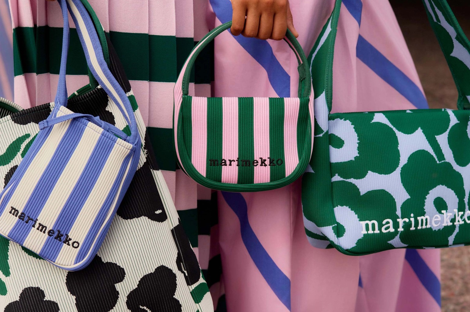Models holding a selection of knitted bags in various color combinations.