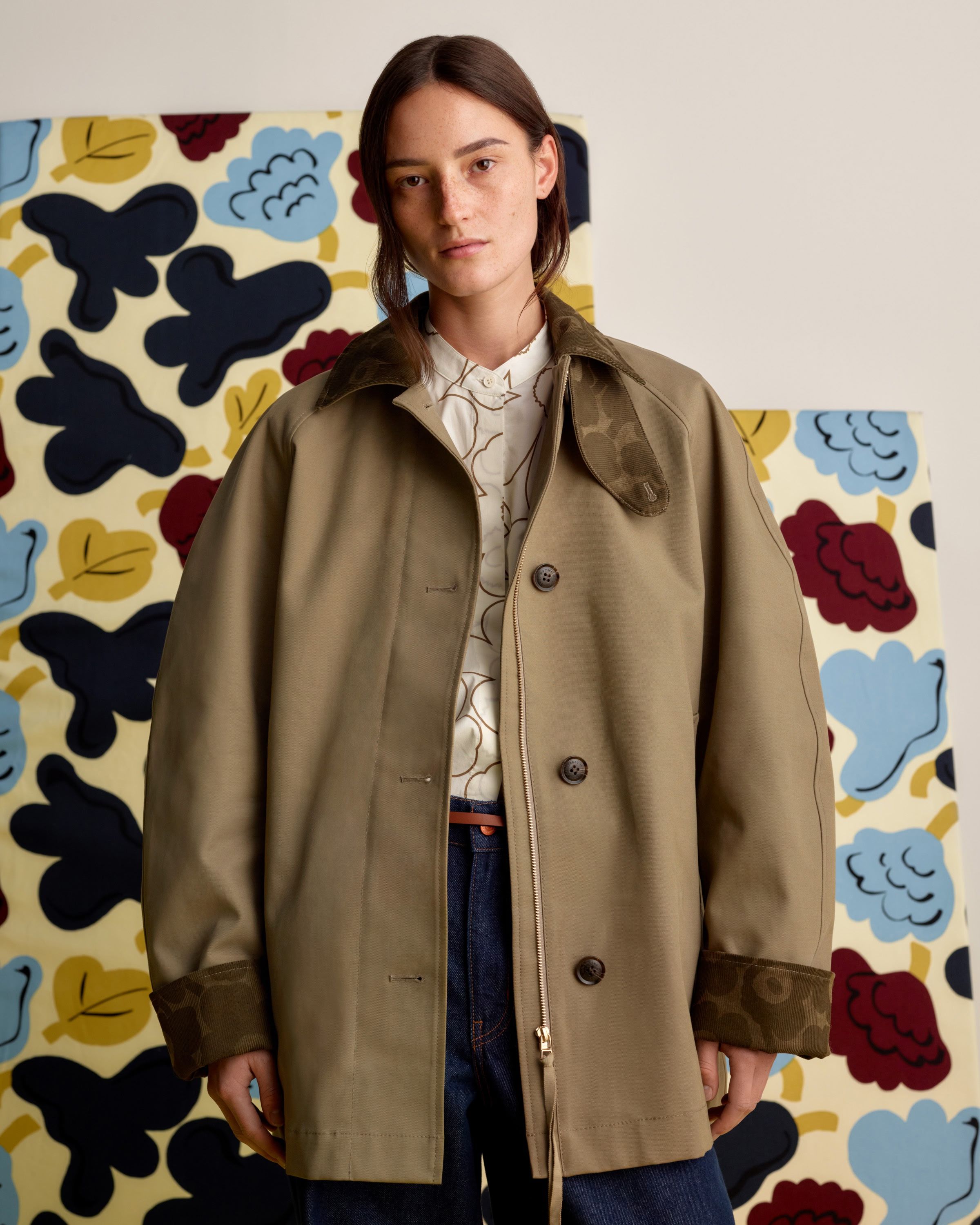 Model wearing light brown coat with dark brown Unikko print in the collar and lining. 