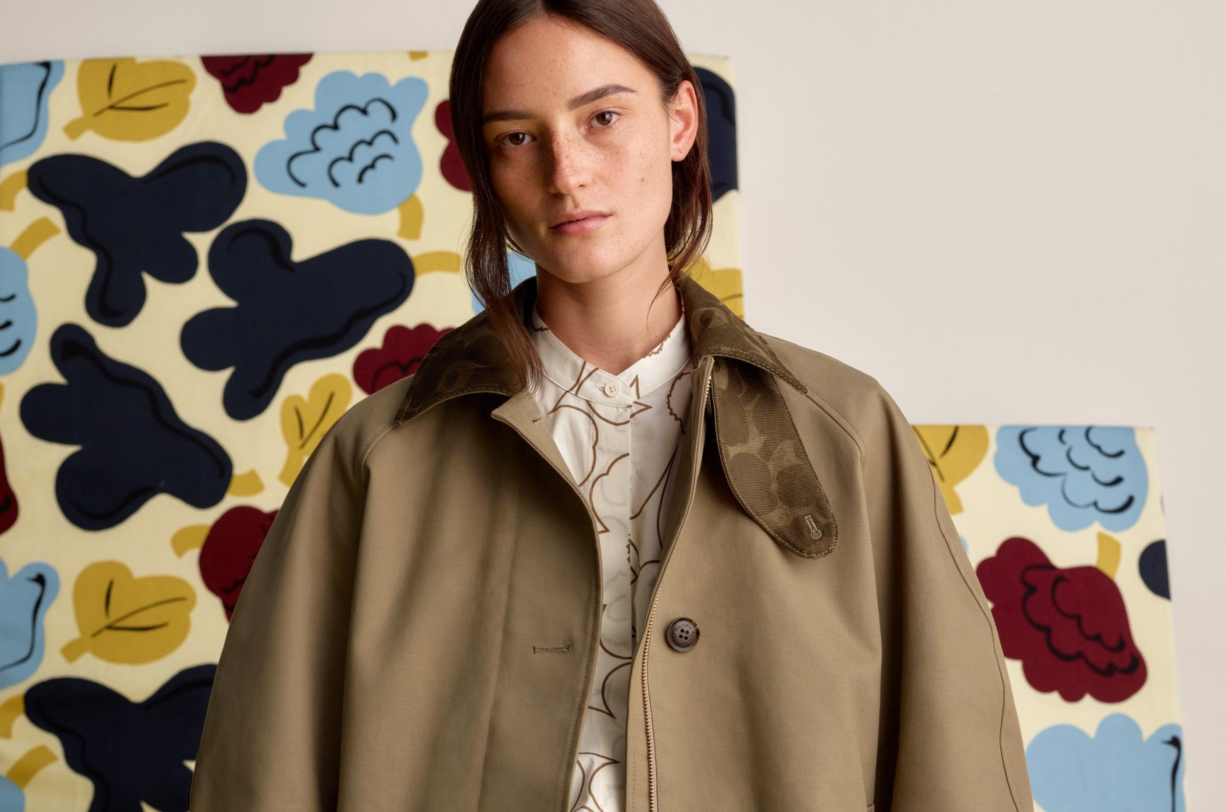 Model wearing light brown coat with dark brown Unikko print in the collar and lining.
