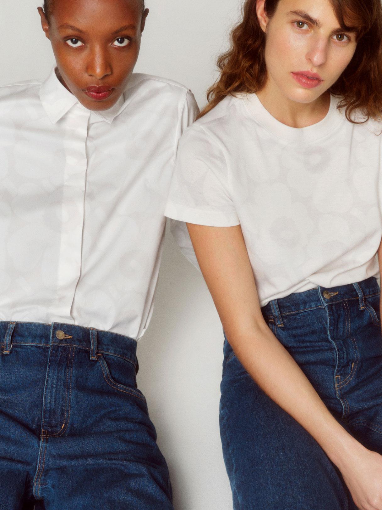 Two models wearing dark blue Marimekko Maridenim jeans and white tops.