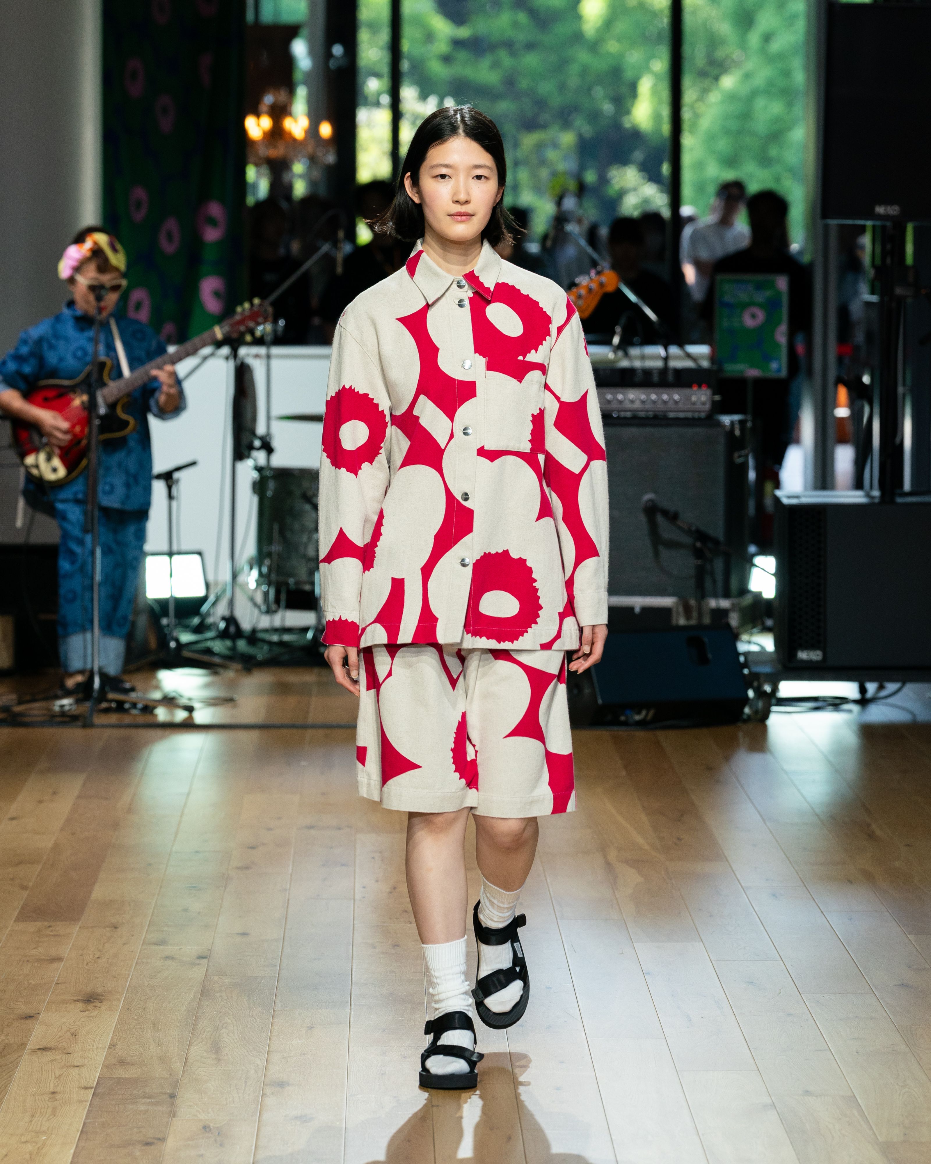 Model wearing oversized pink-white jacket and shorts in Unikko pattern. 