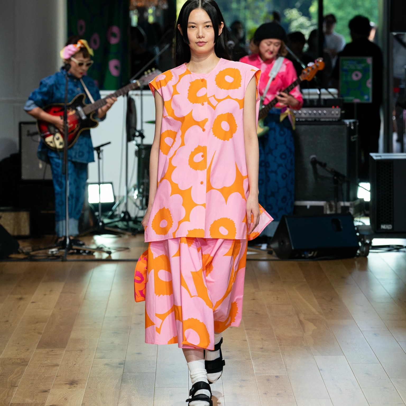 Model wearing orange and pink shirt and skirt in Unikko pattern.