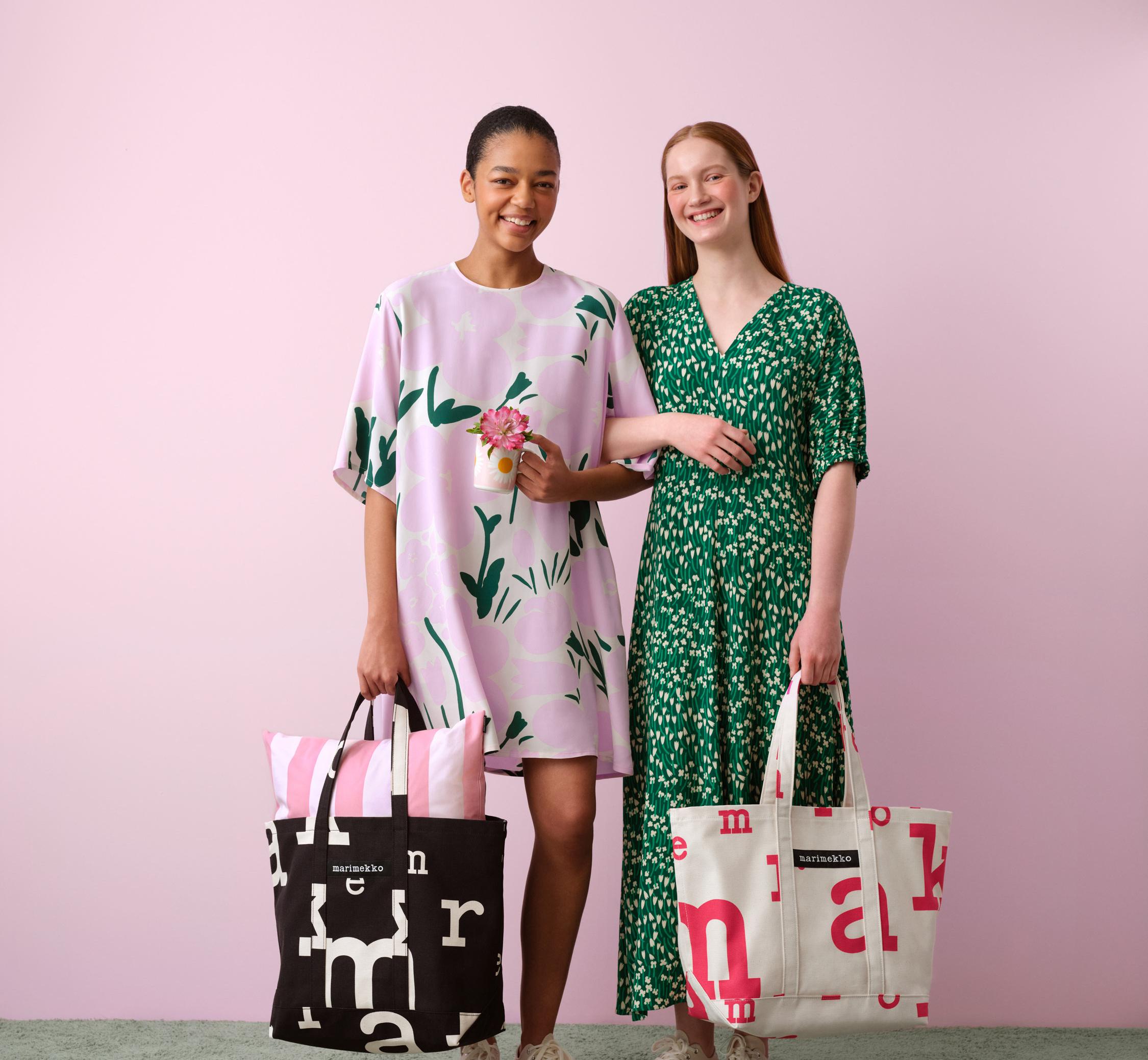 Mallien yllä mekot Tuulahdus- ja Talkoot-kuoseissa ja he pitelevät laukkuja, joissa on Marimerkki-kuosi. Maassa kaksi Auringonkukka-kuosi tyynyä.