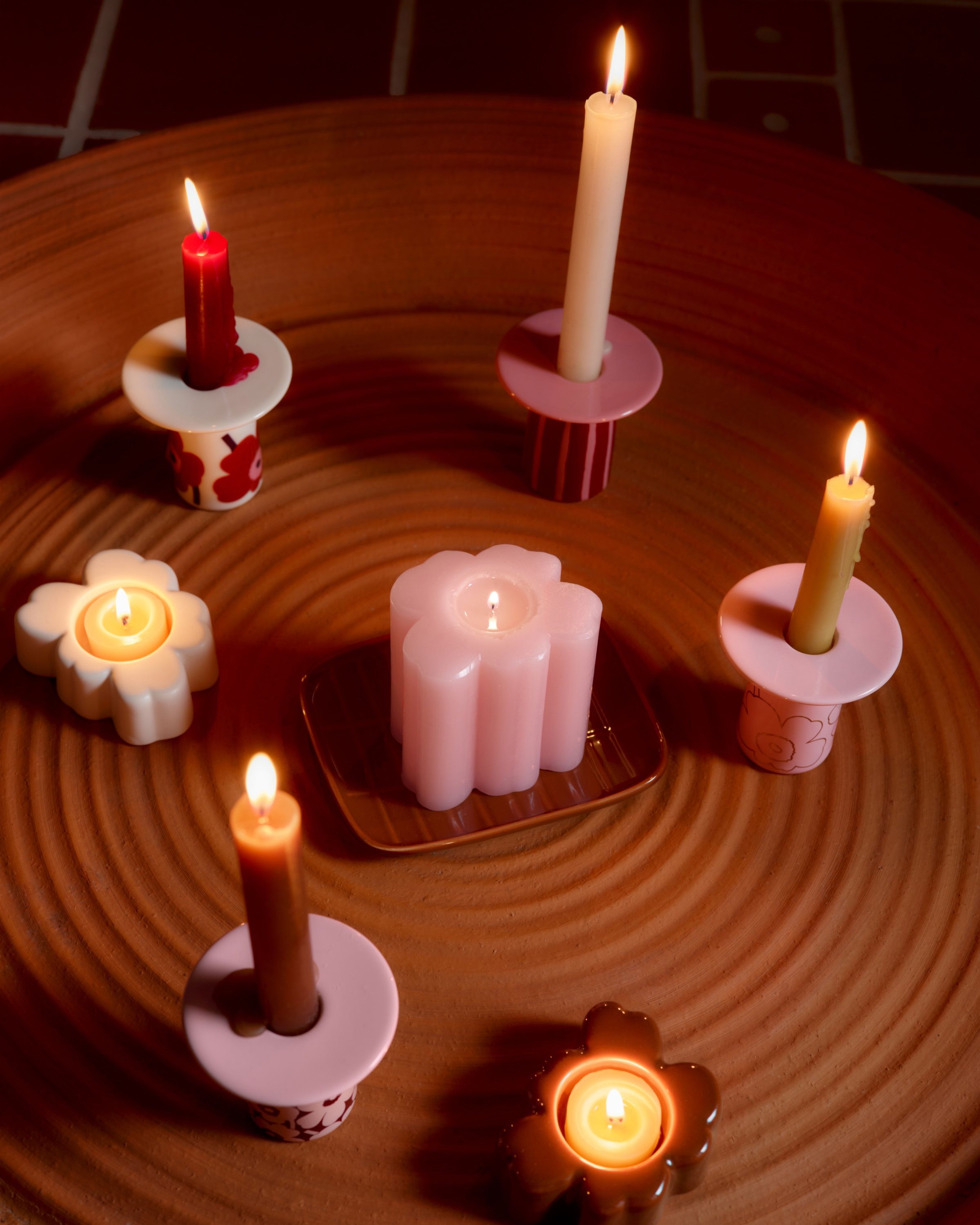 Various Marimekko candle holders in red and pink Unikko and Piccolo prints on a table.