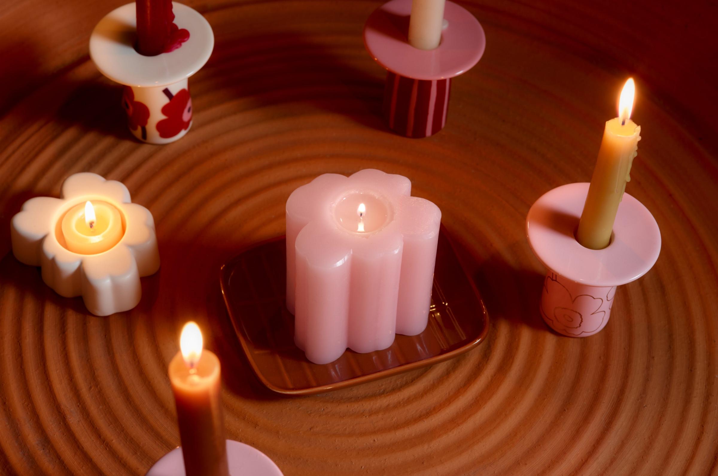 Various Marimekko candle holders in red and pink Unikko and Piccolo prints on a table.