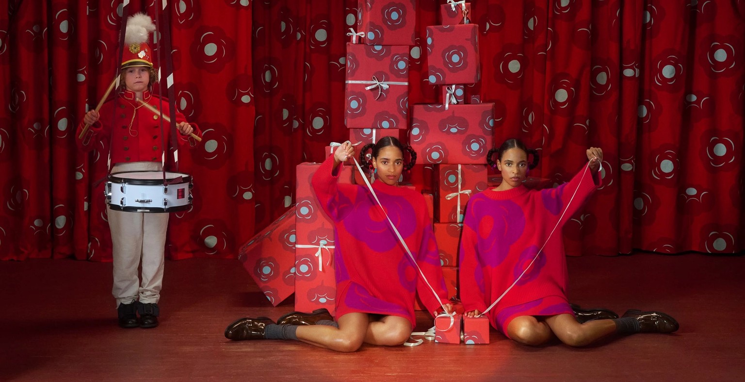 Two models sitting on a stage and a boy playing a drum.