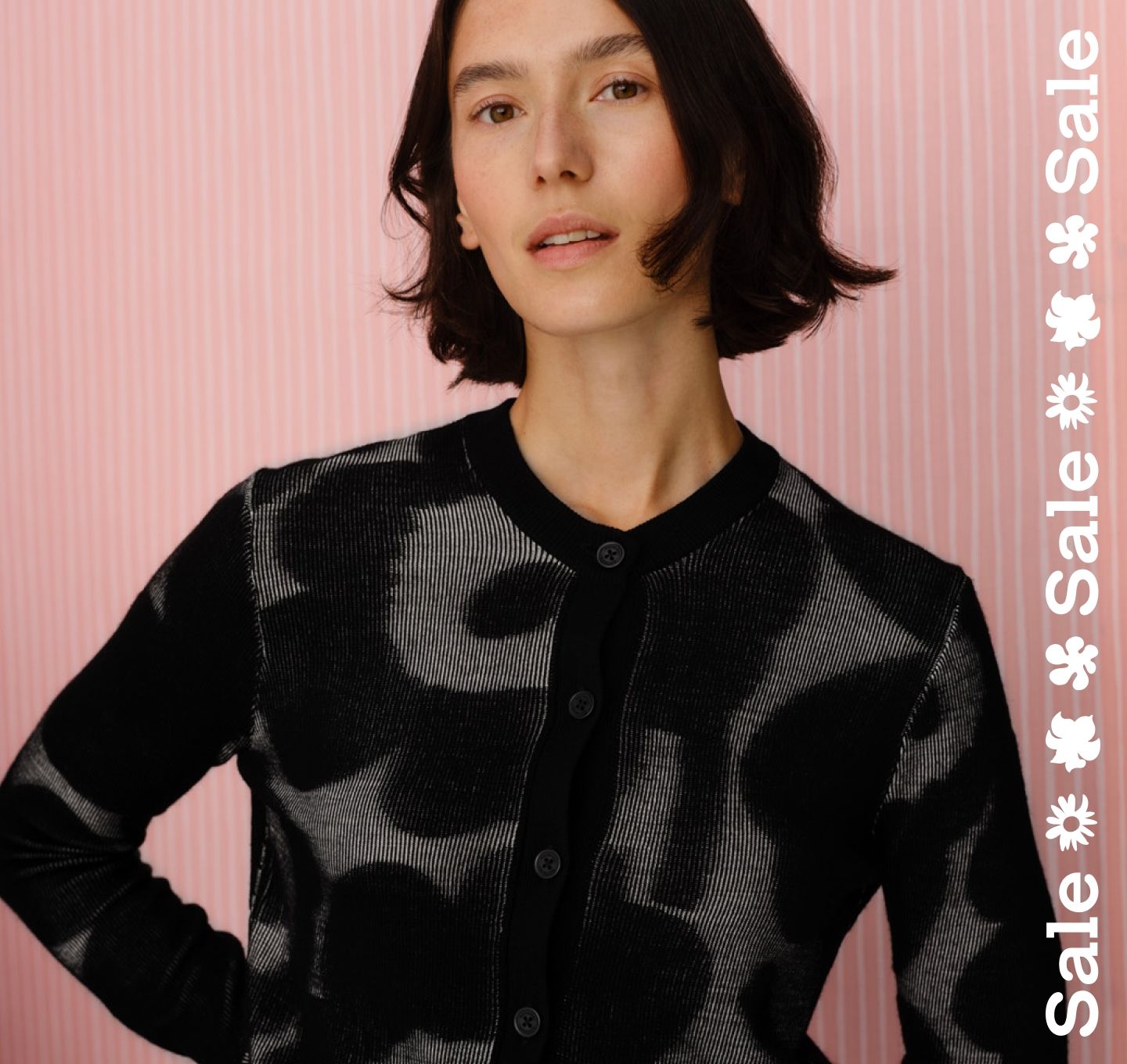 Model wearing Innoitta knit cardigan in Unikko pattern and sale text stripe vertically on the right.