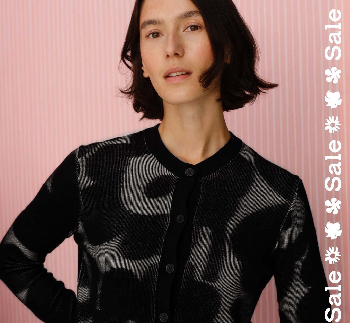 Model wearing Innoitta knit cardigan in Unikko pattern and sale text stripe vertically on the right.