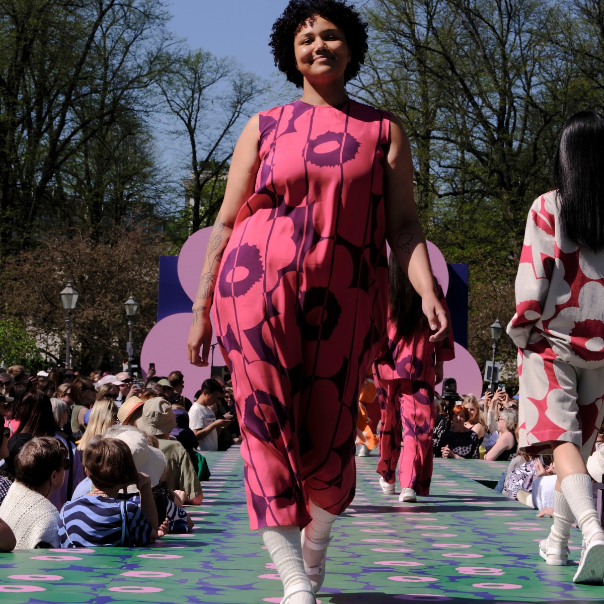 The model is dressed in a pink-purple cupro dress with a Unikko pattern.