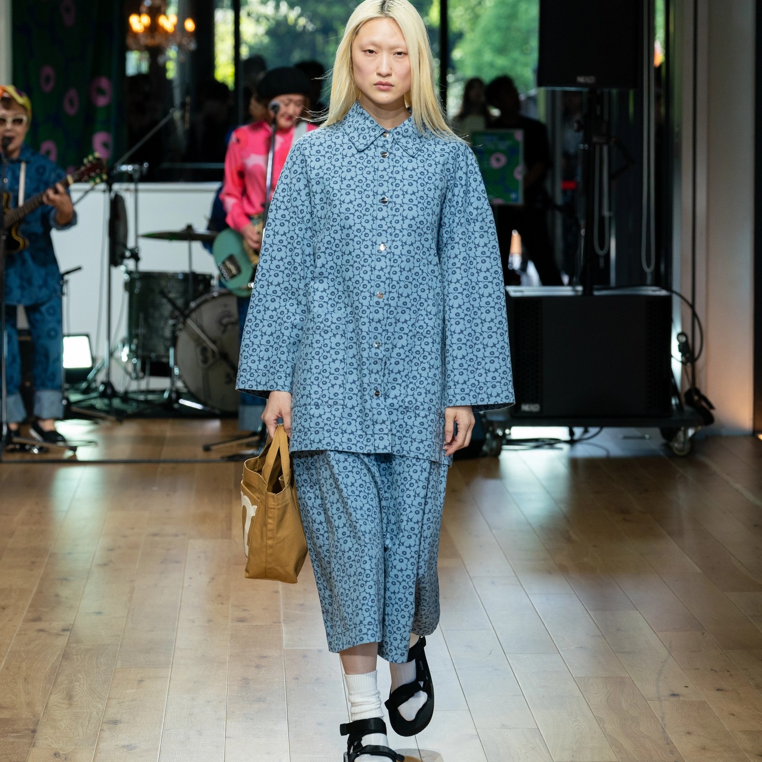 Model wearing blue jacket and skirt with small Unikko patterns.