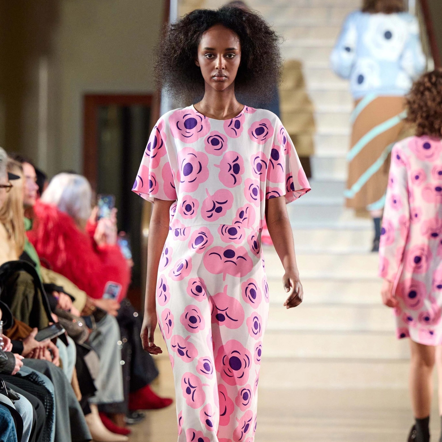 A model walks in the Marimekko fashion show wearing a pink dress with the Tumma pattern