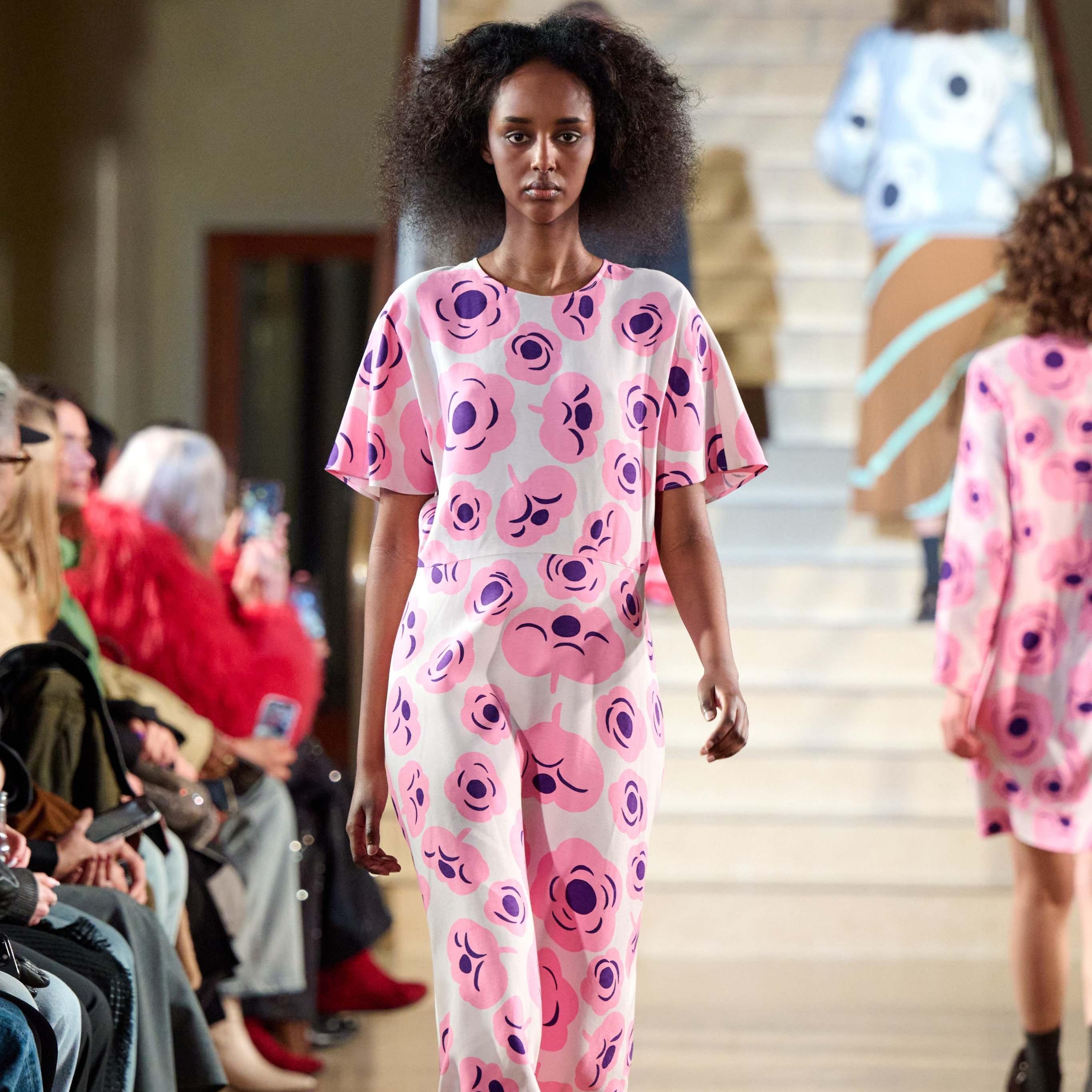 A model walks in the Marimekko fashion show wearing a pink dress with the Tumma pattern