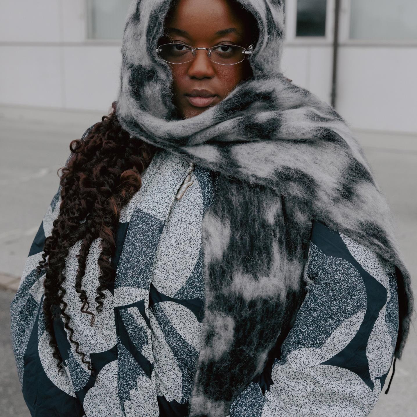 Ashlyn Delaney wrapped in a black and white quilted jacket and scarf with a Unikko pattern.