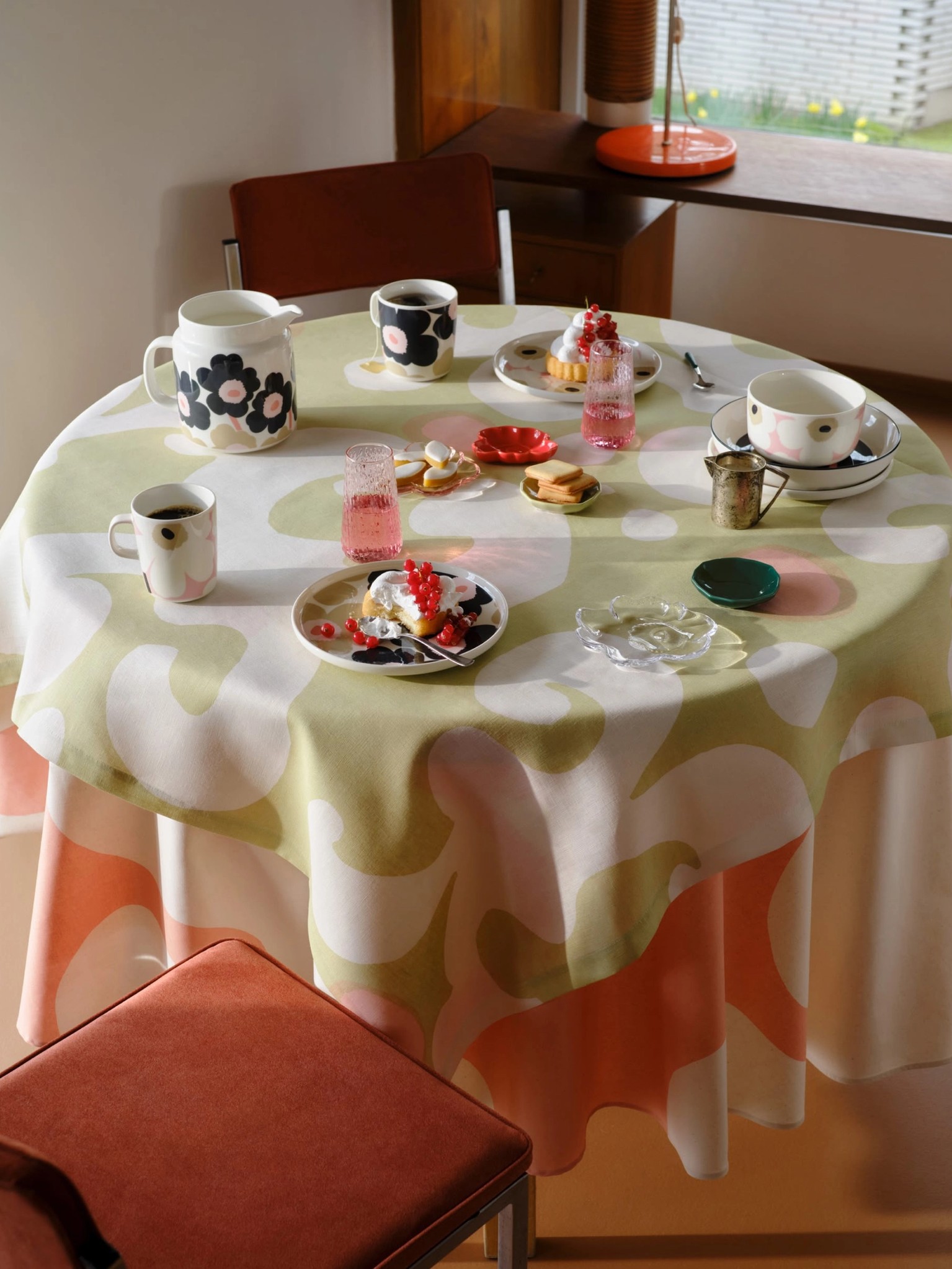 A set table with dishes and a light green Keidas fabric tablecloth.