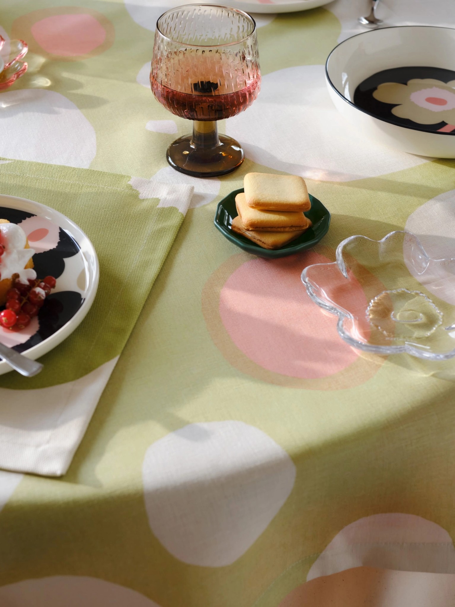 A set table with dishes and a light green Keidas fabric tablecloth.