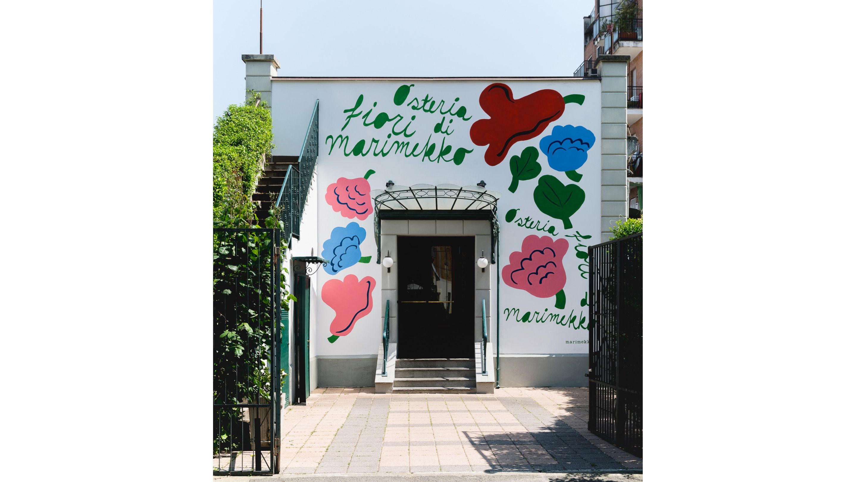 Exterior of a house featuring the Kukasta kukkaan pattern painted on it, along with the text “Osteria Fiori di Marimekko.”
