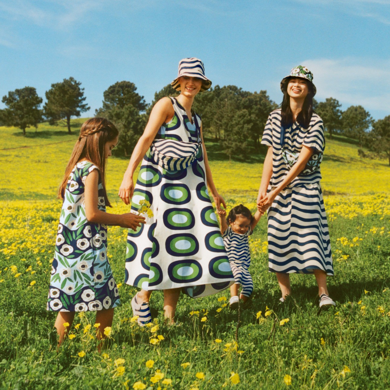 Enfants et femme portant des vêtements de la collaboration Uniqlo et Marimekko dans un champ de fleurs