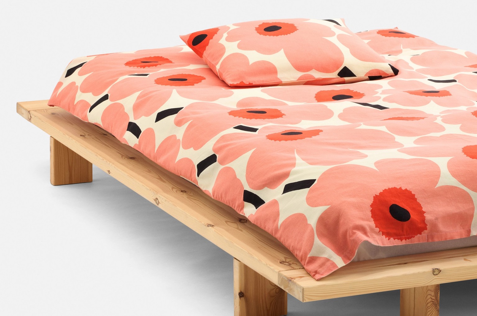 A made bed with Unikko pattern sheets red and peach.