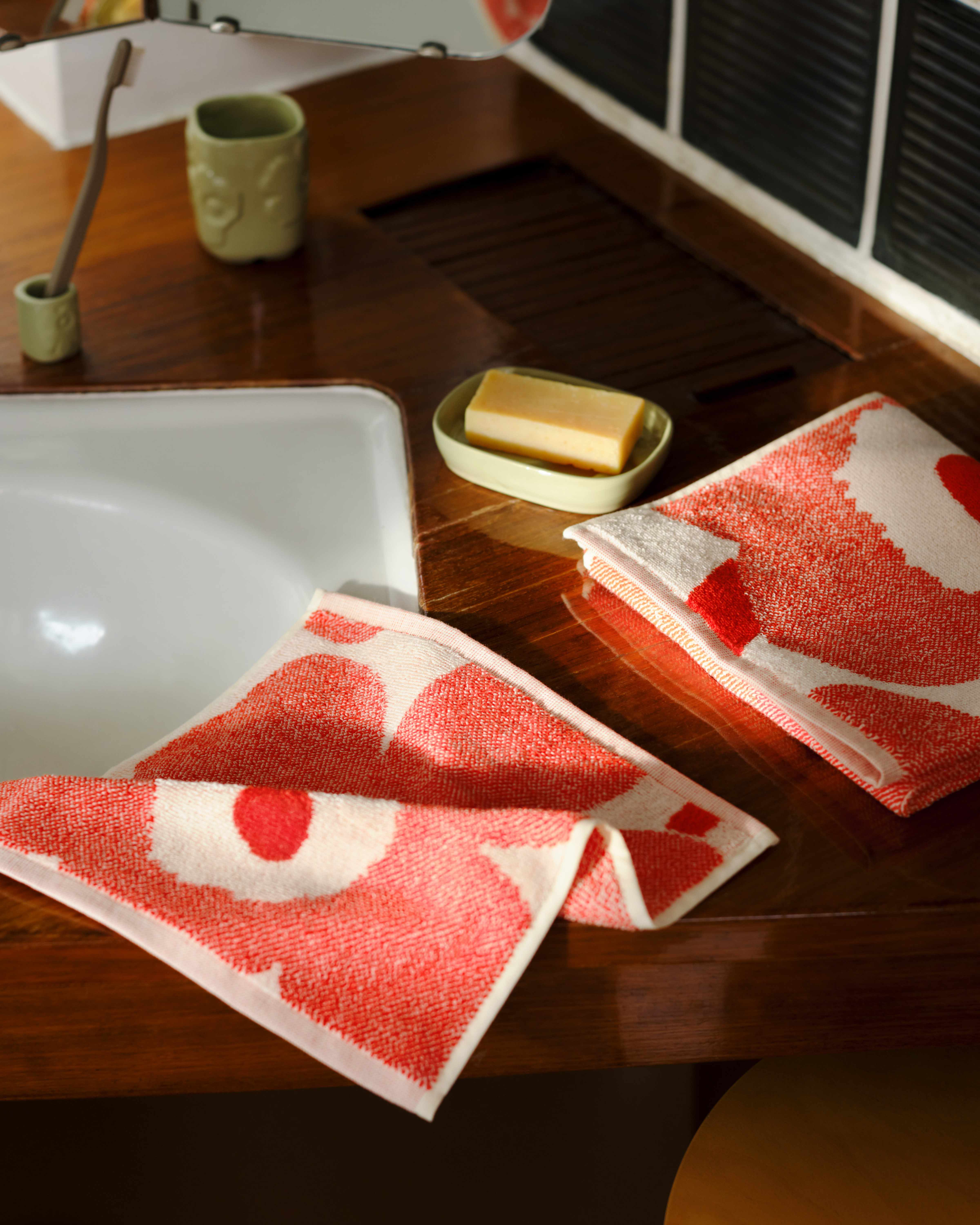 Marimekko towels in red and white Unikko print on a bathroom counter.