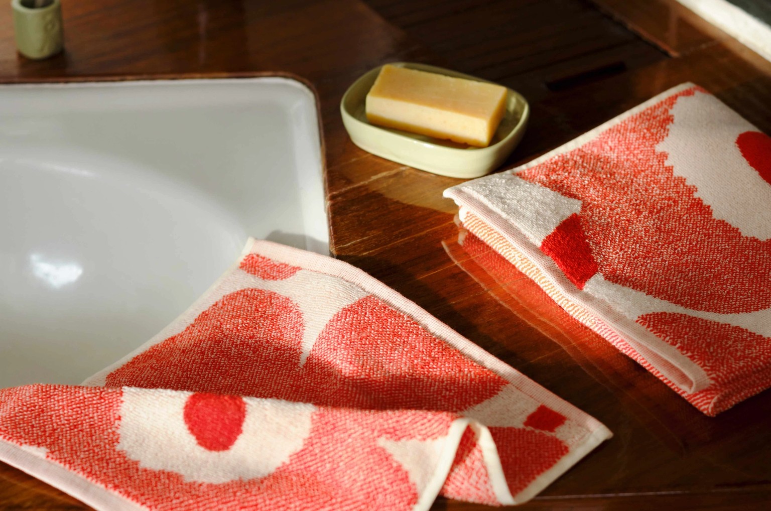 Marimekko towels in red and white Unikko print on a bathroom counter.