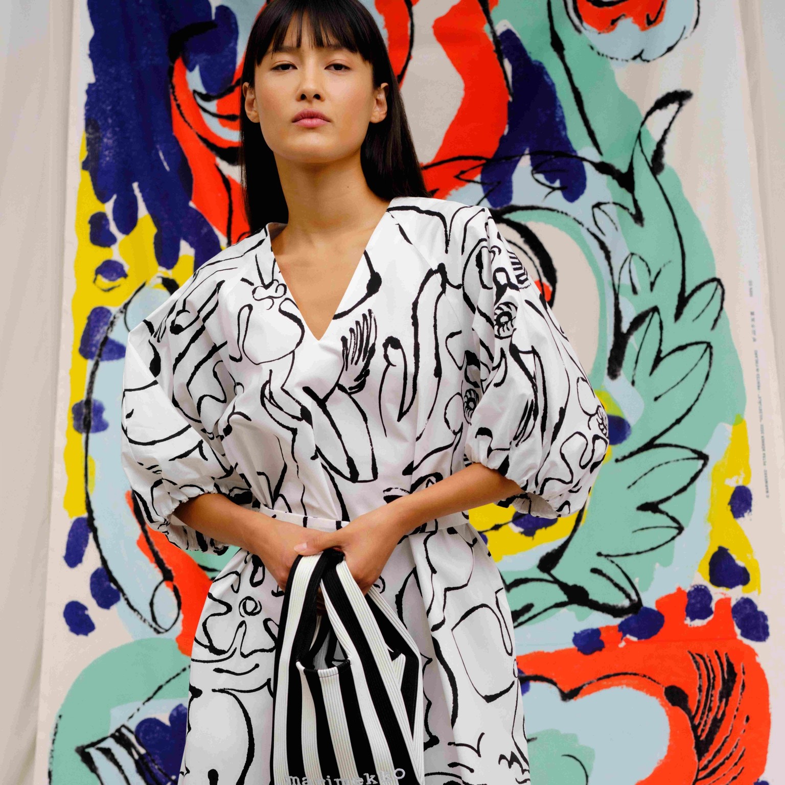 The model dressed in a black and white dress from collaboration with Petra Börner. In the background, Petra Börner's colorful artwork printed on fabric.
