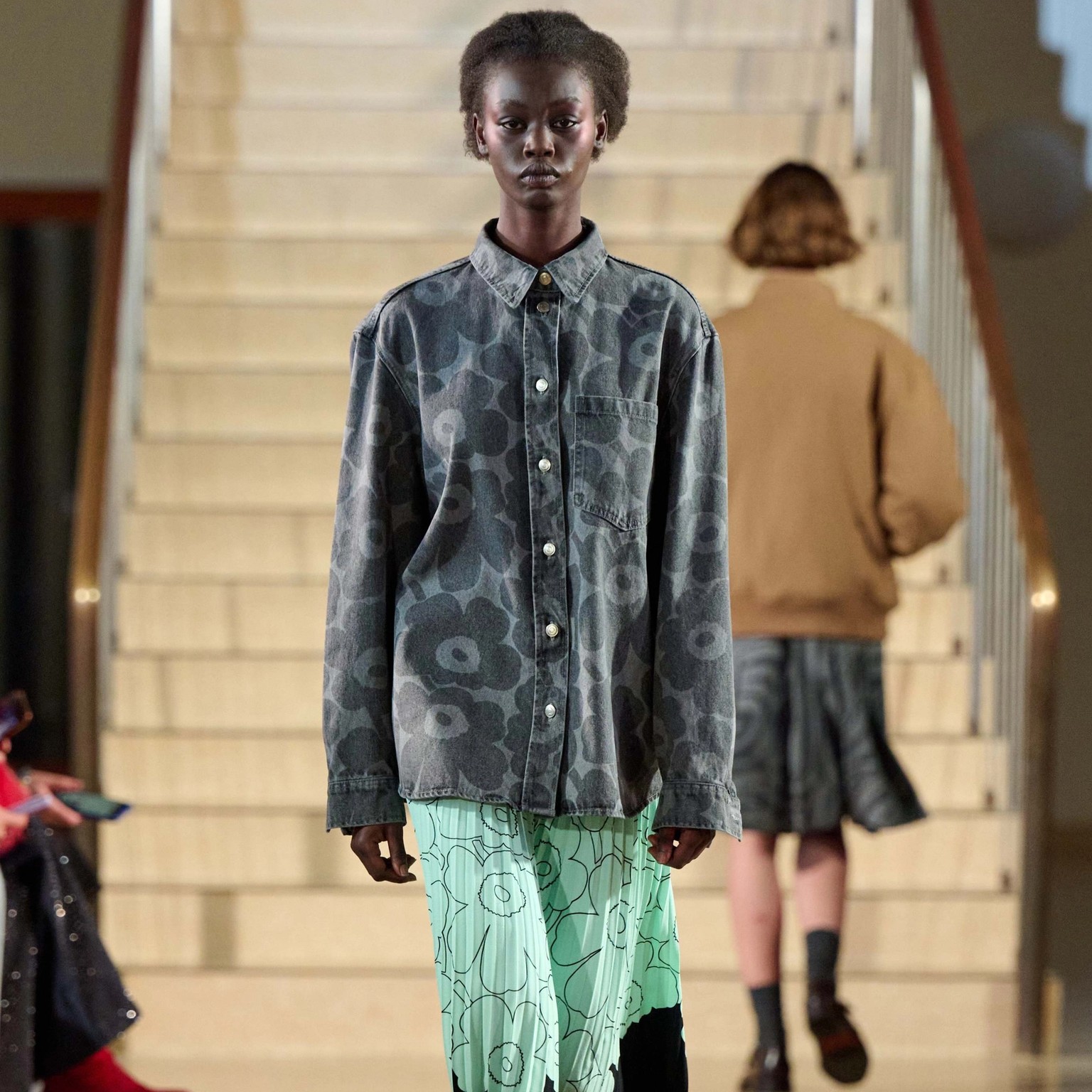 A model walking in Marimekko's fashion show wearing grey Maridenim shirt and mint colored Myy-skirt