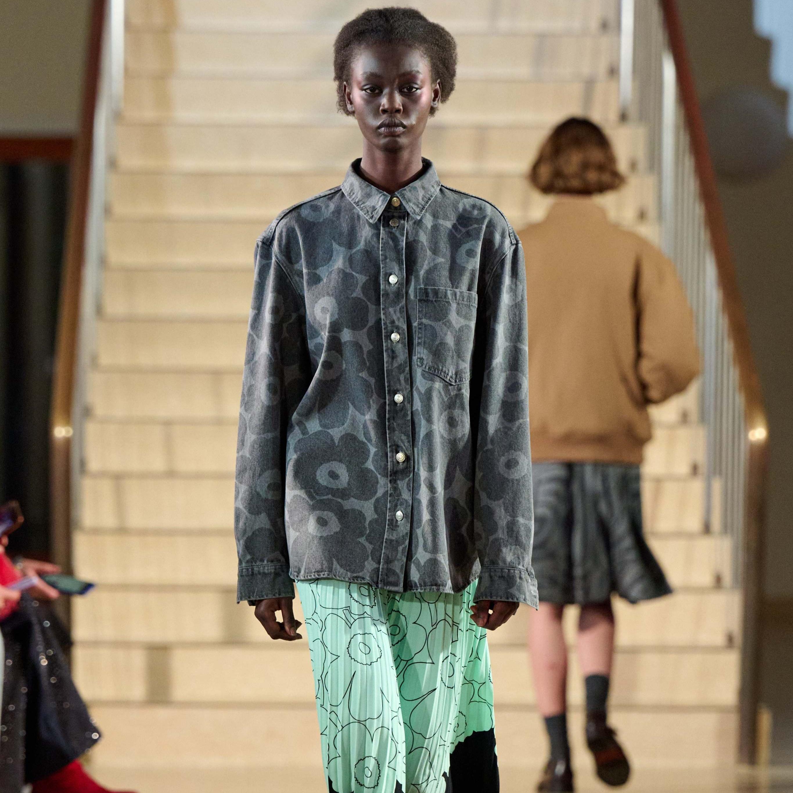 A model walking in Marimekko's fashion show wearing grey Maridenim shirt and mint colored Myy-skirt