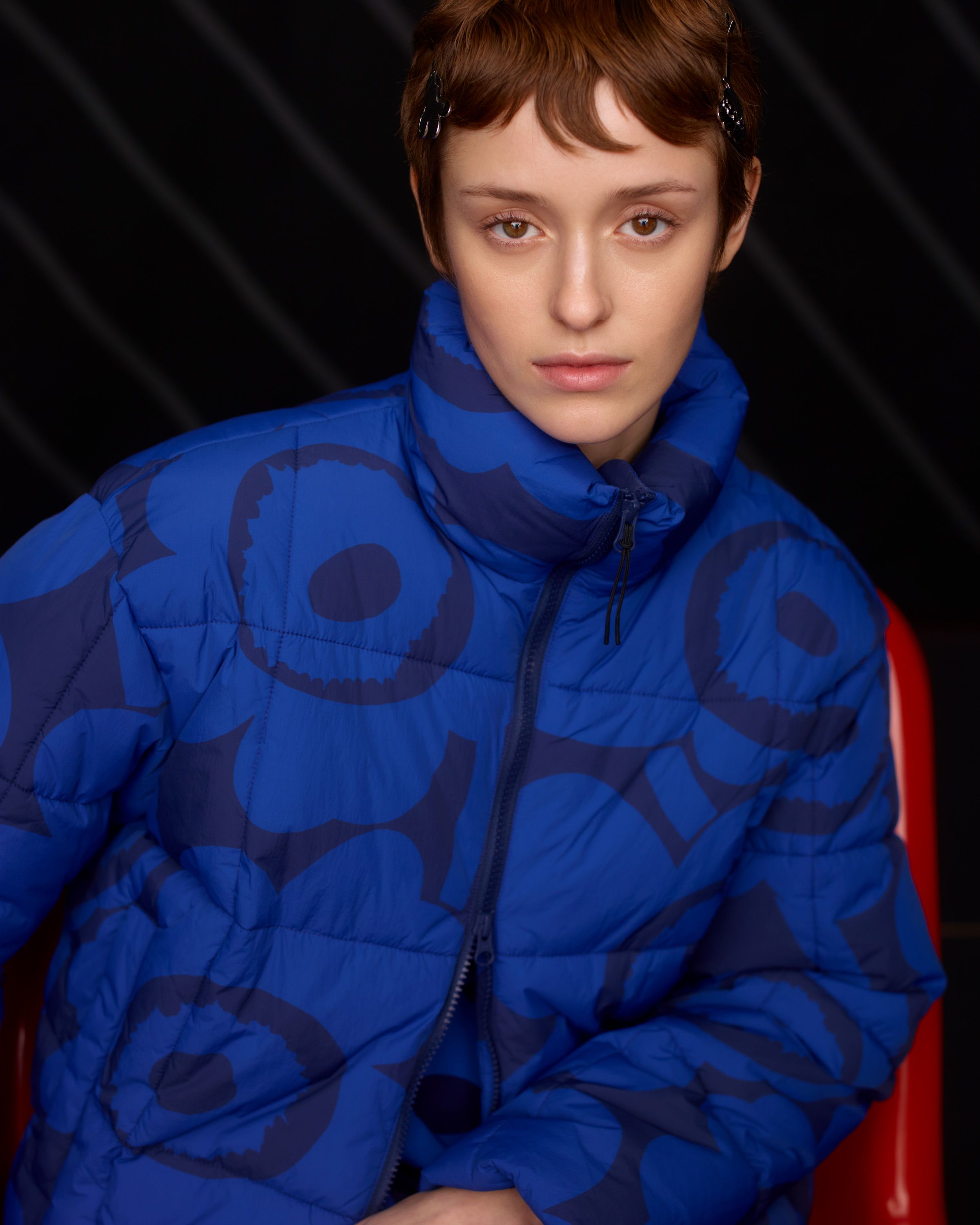 Model wearing a cropped Marimekko puffer jacket in black and blue Unikko print.